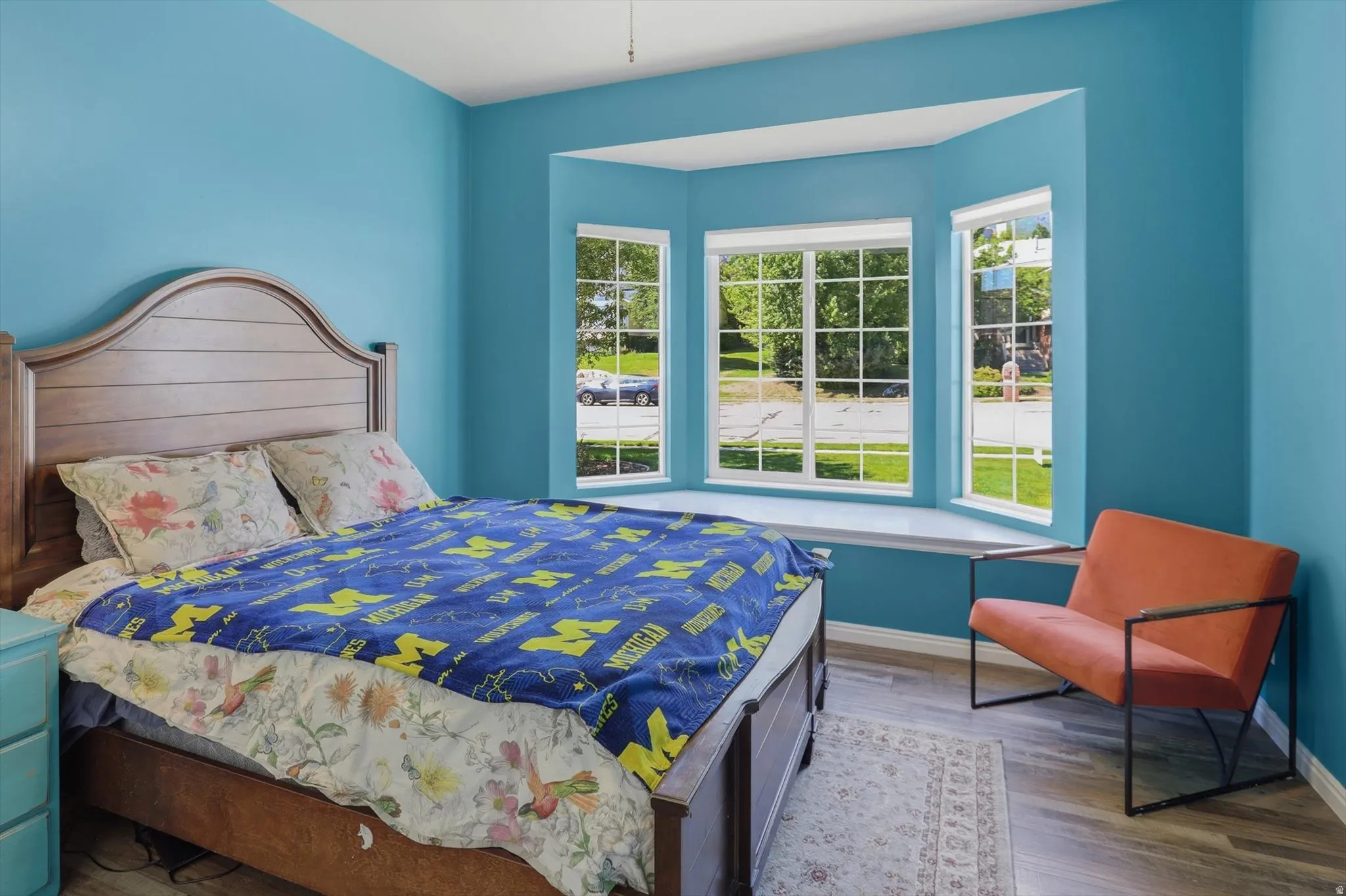 Spacious room featuring a multi-pane bay window with a wide sill, light wood-finish flooring, and a ceiling fan
