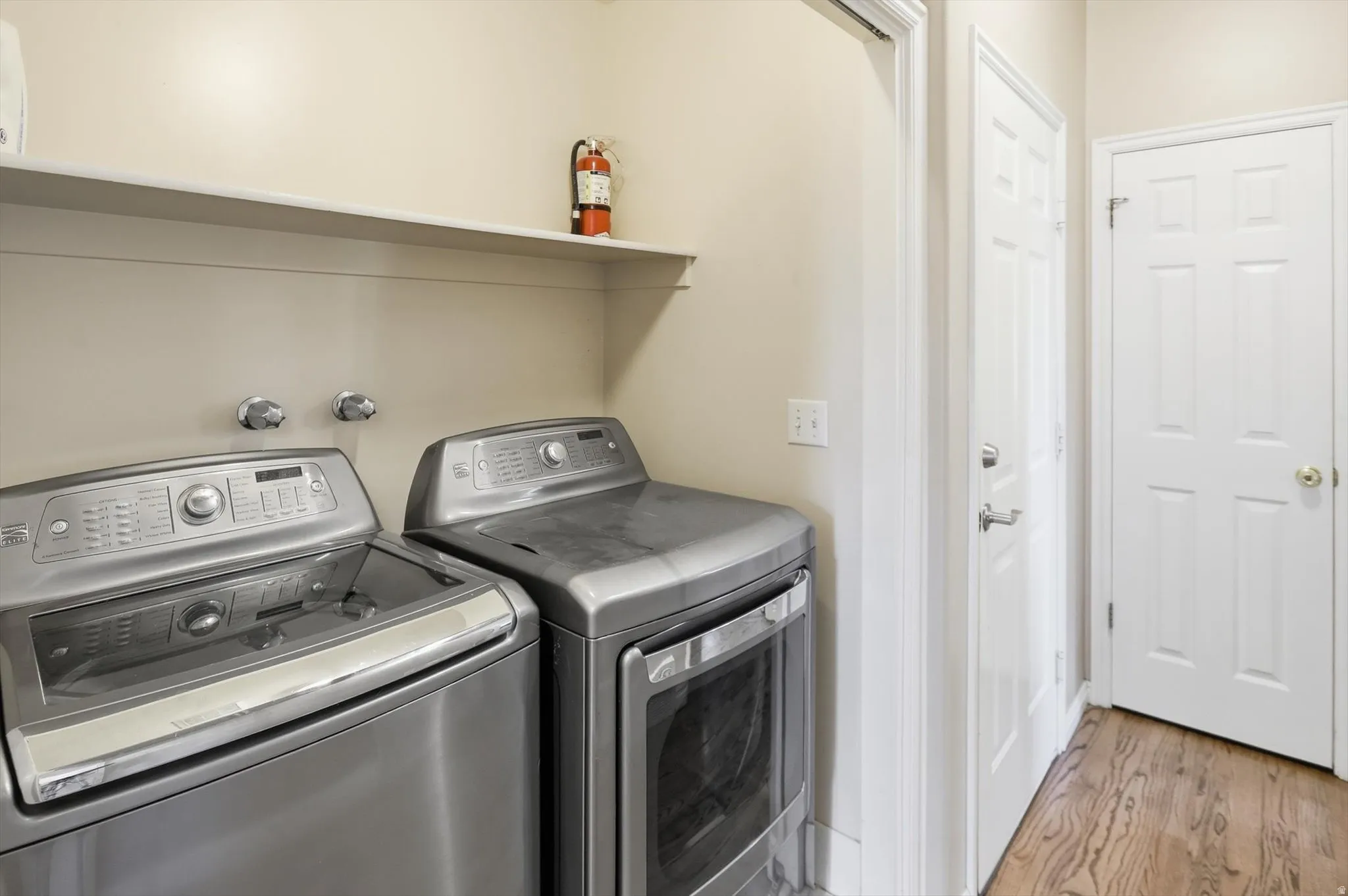 Dedicated laundry area featuring a built-in shelf, side-by-side appliance hookups, and wood-finish flooring