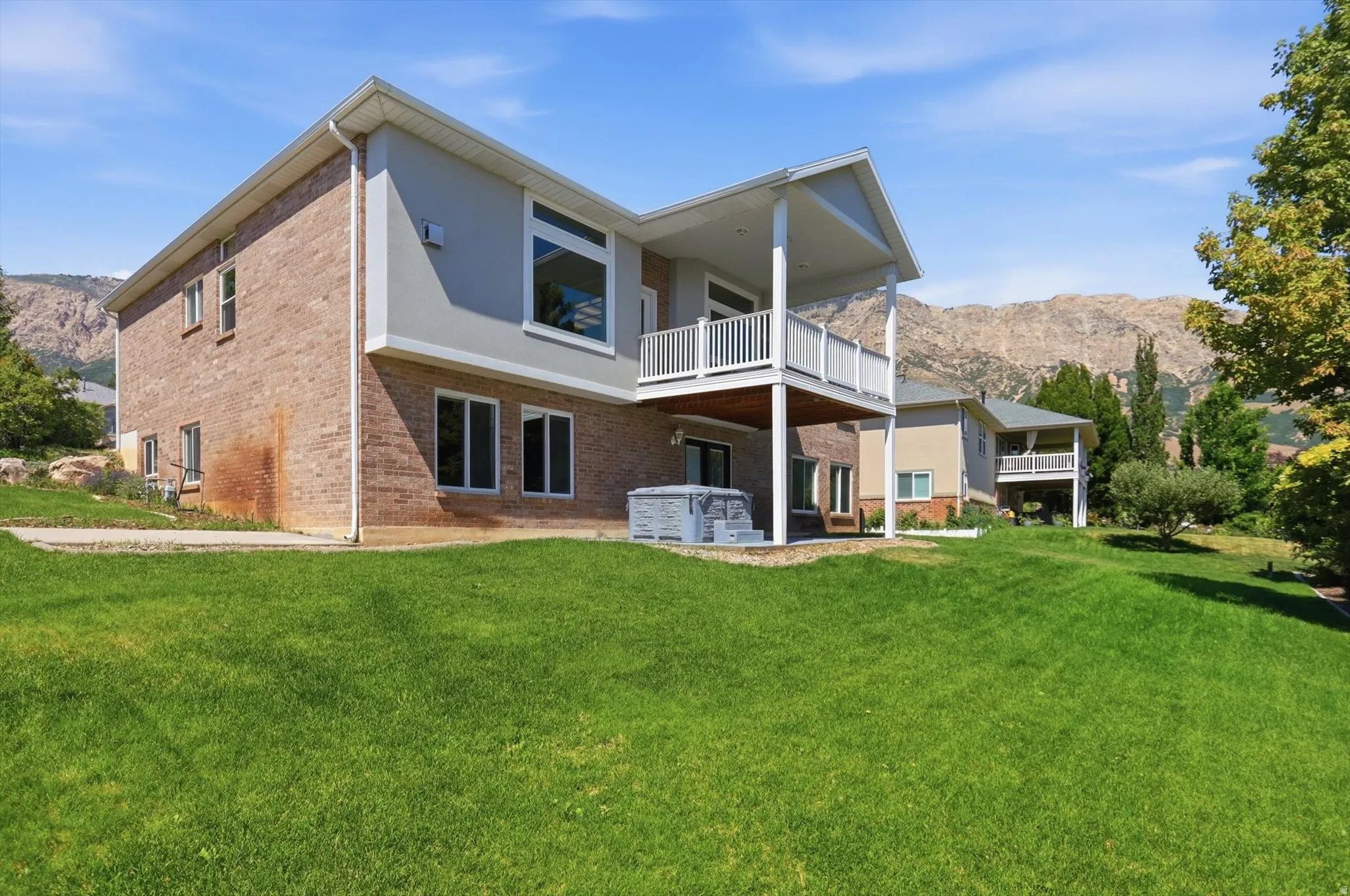 Expansive grassy yard featuring a multi-level dwelling with a brick and stucco exterior