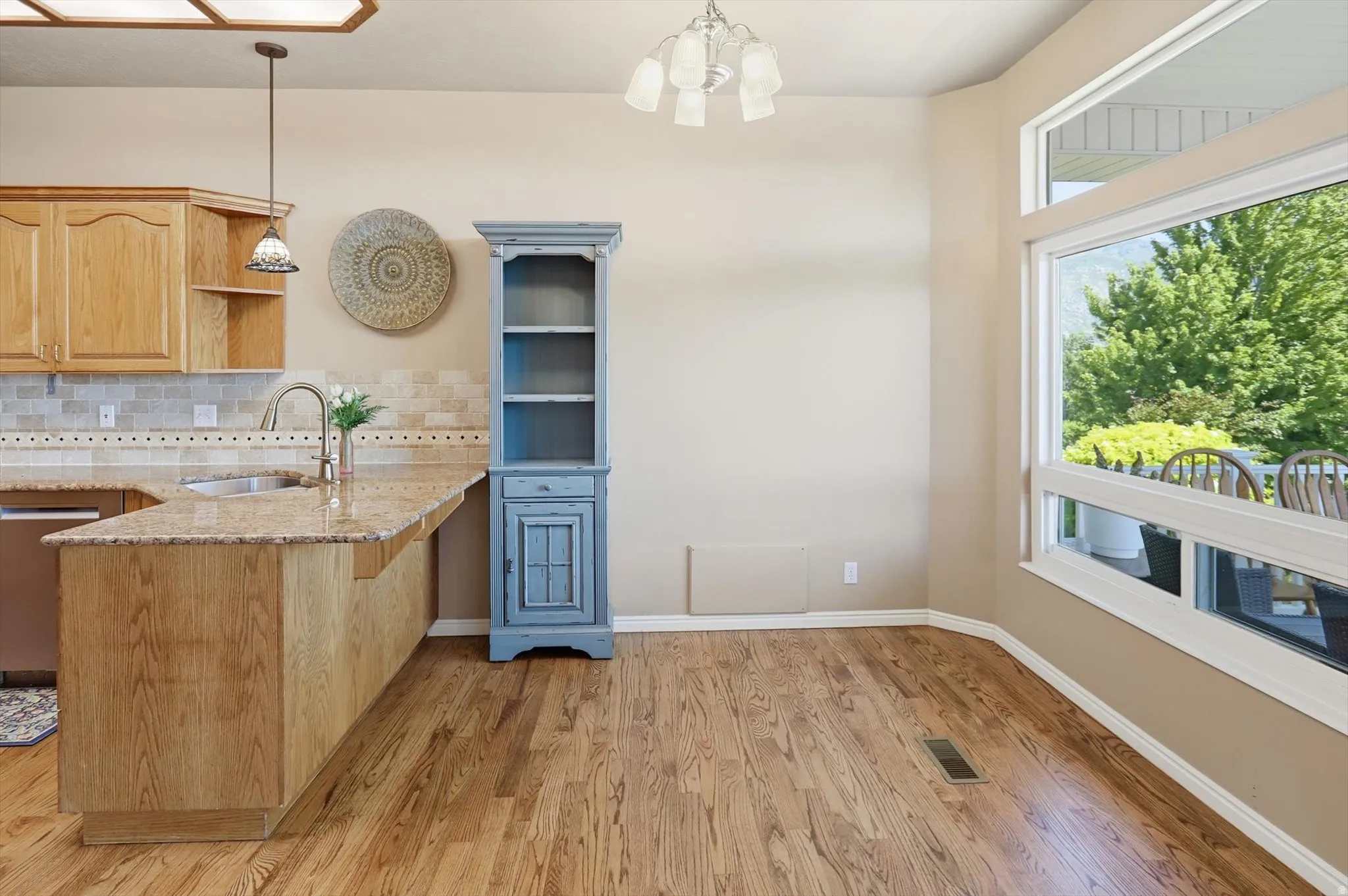 Open-concept living space featuring wood-finish flooring, a kitchen island with stone countertops, and a tile backsplash