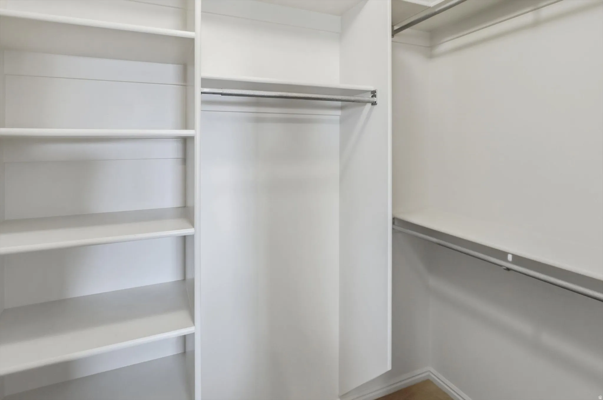 White shelving system featuring multiple adjustable shelves, integrated hanging rods, and a neutral wall finish