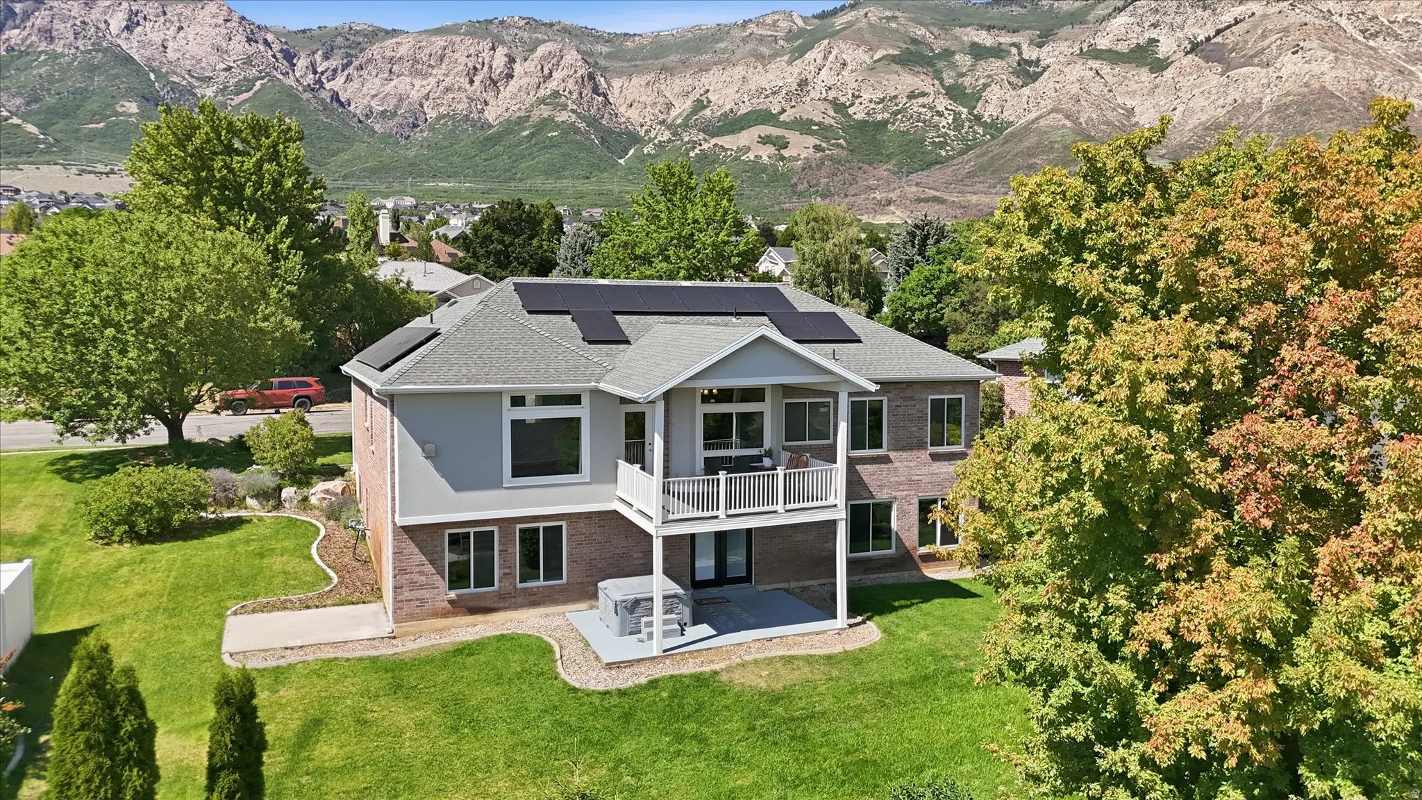 Two-story residence featuring brick and siding exterior, a second-story balcony, and a ground-level patio