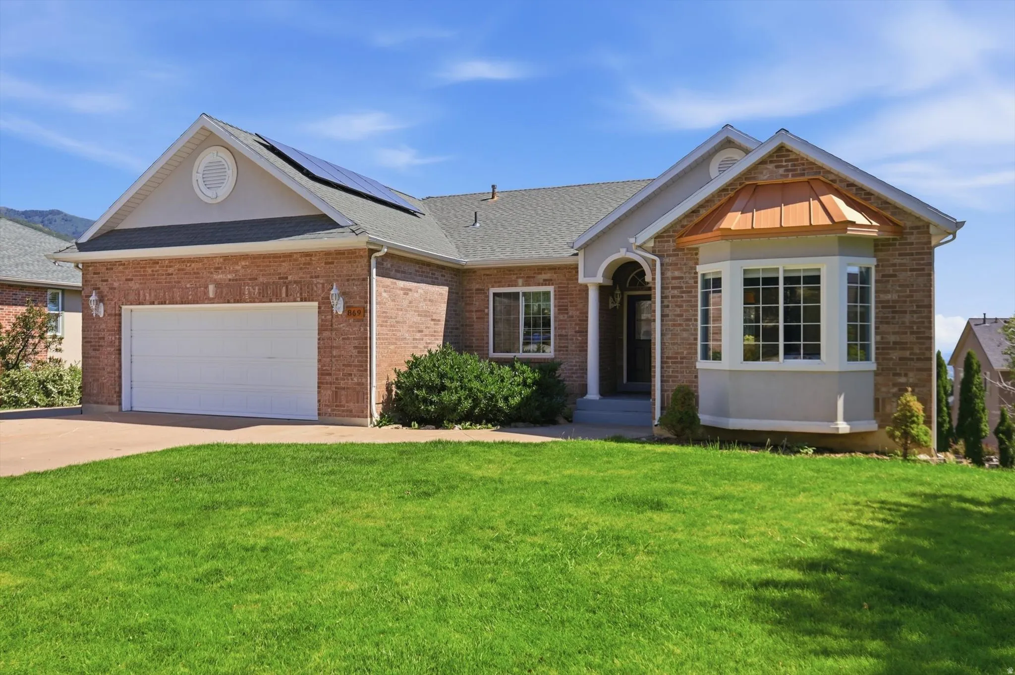 Brick facade residence featuring a prominent bay window with a copper-tone roof accent