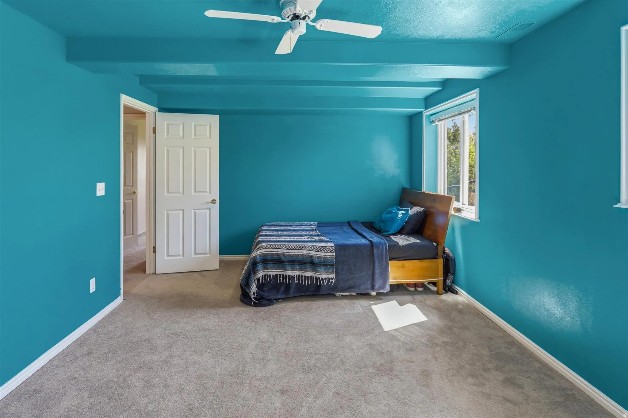 Room featuring carpet flooring, painted walls, a window with exterior views, and a ceiling fan