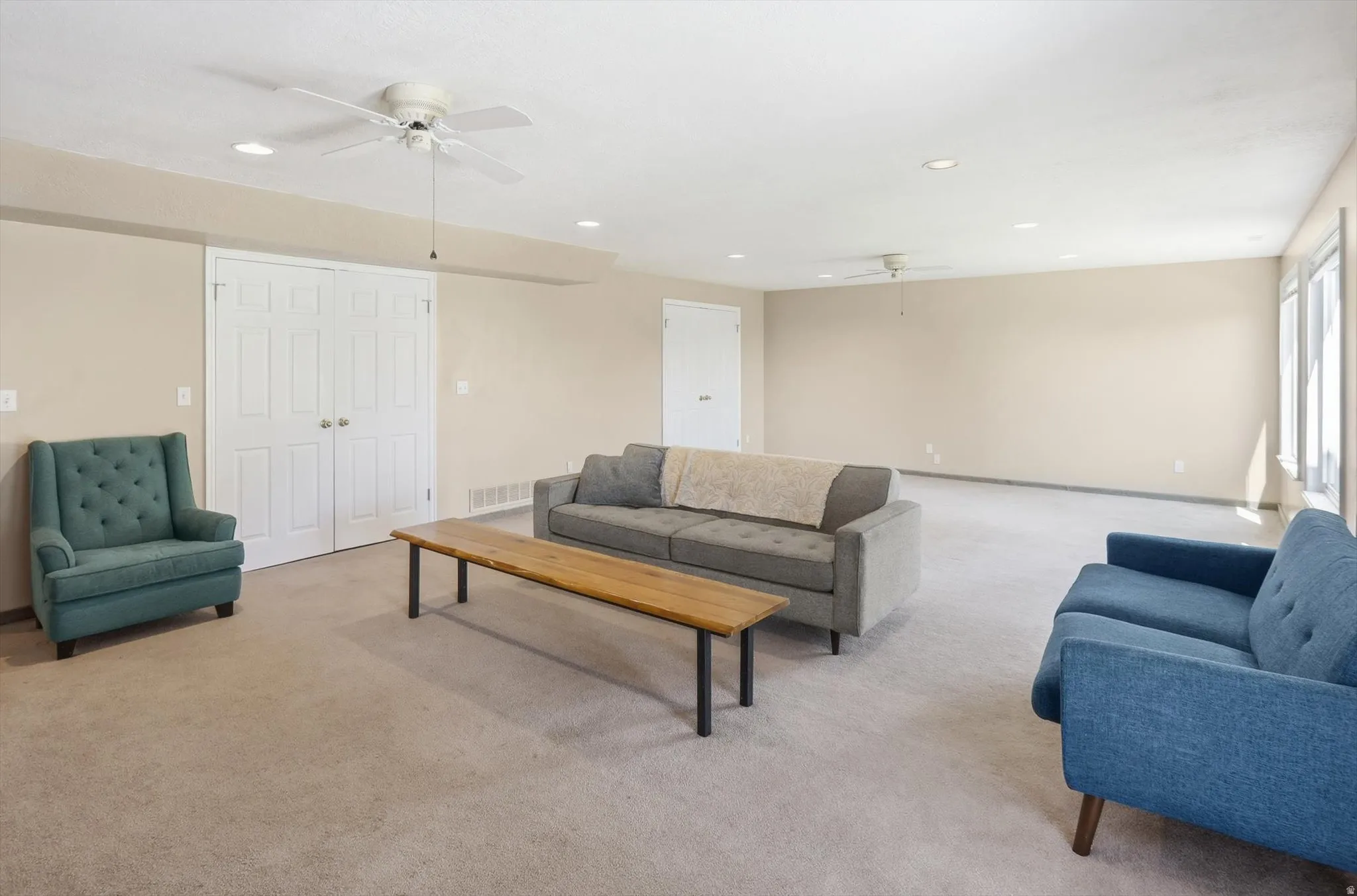 Spacious room featuring neutral carpeting and wall tones, recessed lighting, and multiple ceiling fans