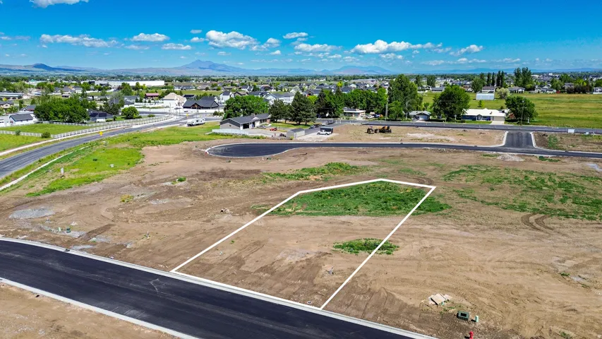 Aerial perspective of a developed lot with partial ground cover, bordered by newly paved roads