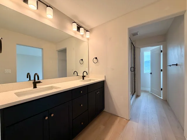 Double vanity with integrated sinks, light-toned countertop, and dark cabinetry