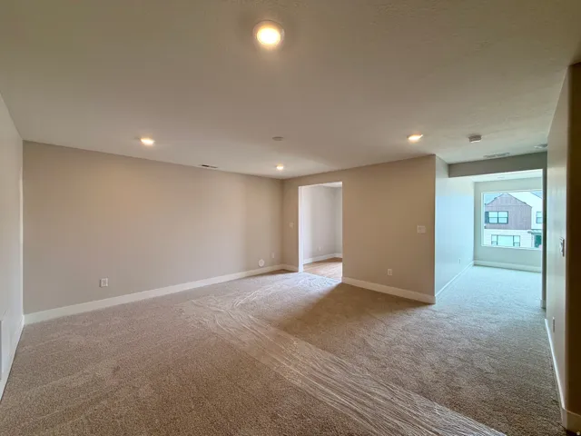 Spacious room featuring neutral carpeting and recessed lighting
