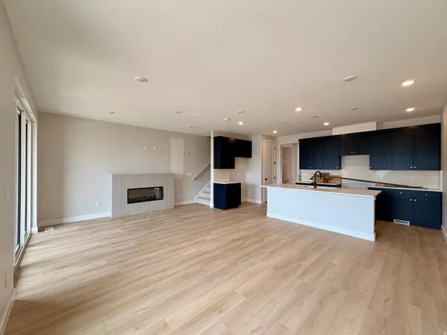 Open-concept living space featuring wood-finish flooring, recessed lighting, and a linear fireplace with a tiled surround