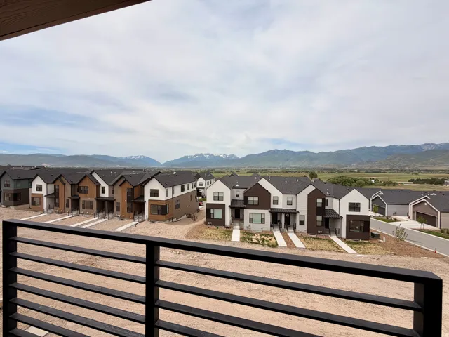 Expansive mountain scenery framing modern townhomes with black roofs, white and brown siding, and paved driveways