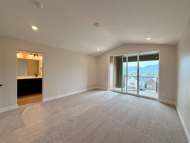 Spacious room featuring vaulted ceilings, recessed lighting, and soft carpeting