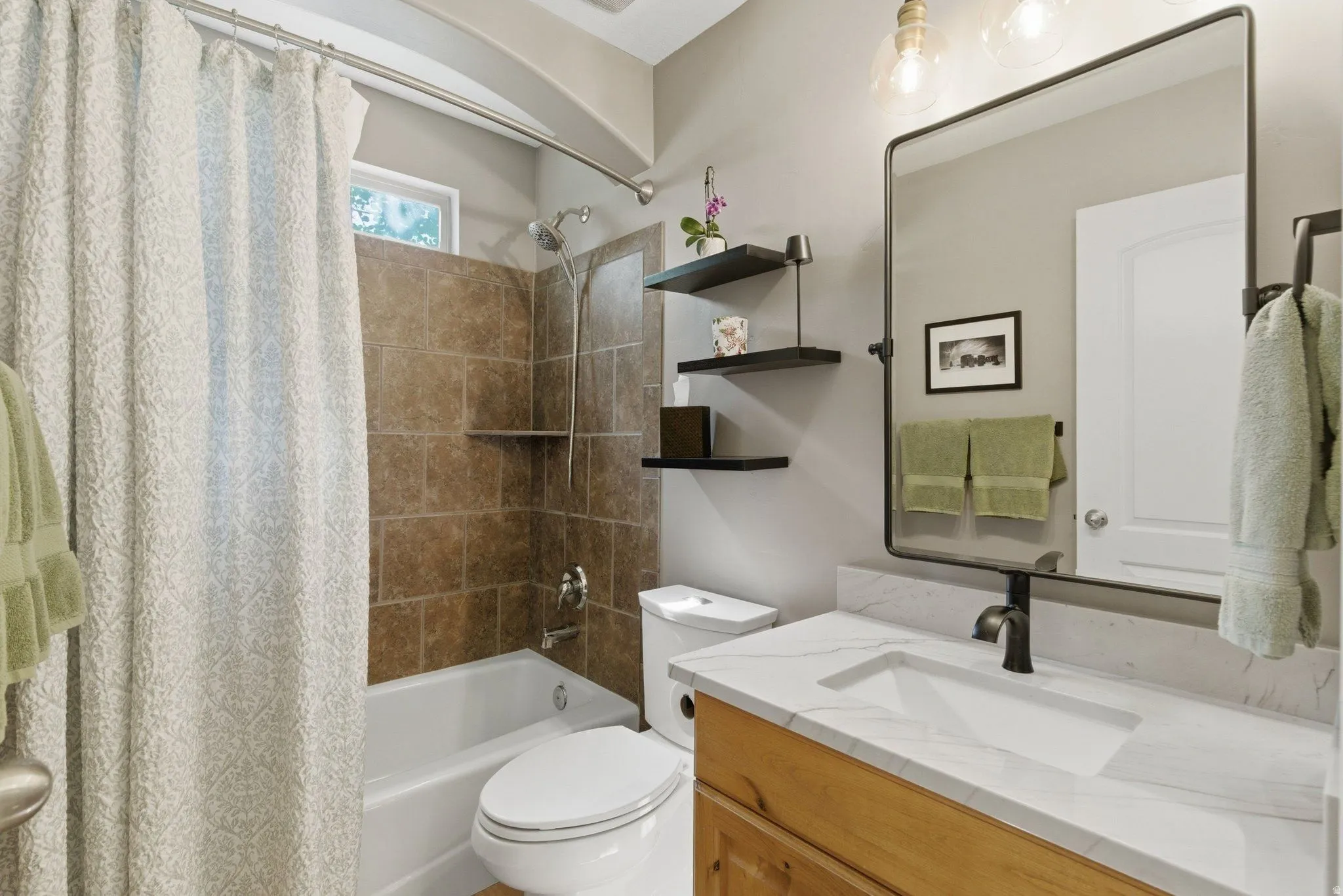 Bathroom featuring a tub/shower combination with brown subway tile surround, a built-in shower shelf, and a window