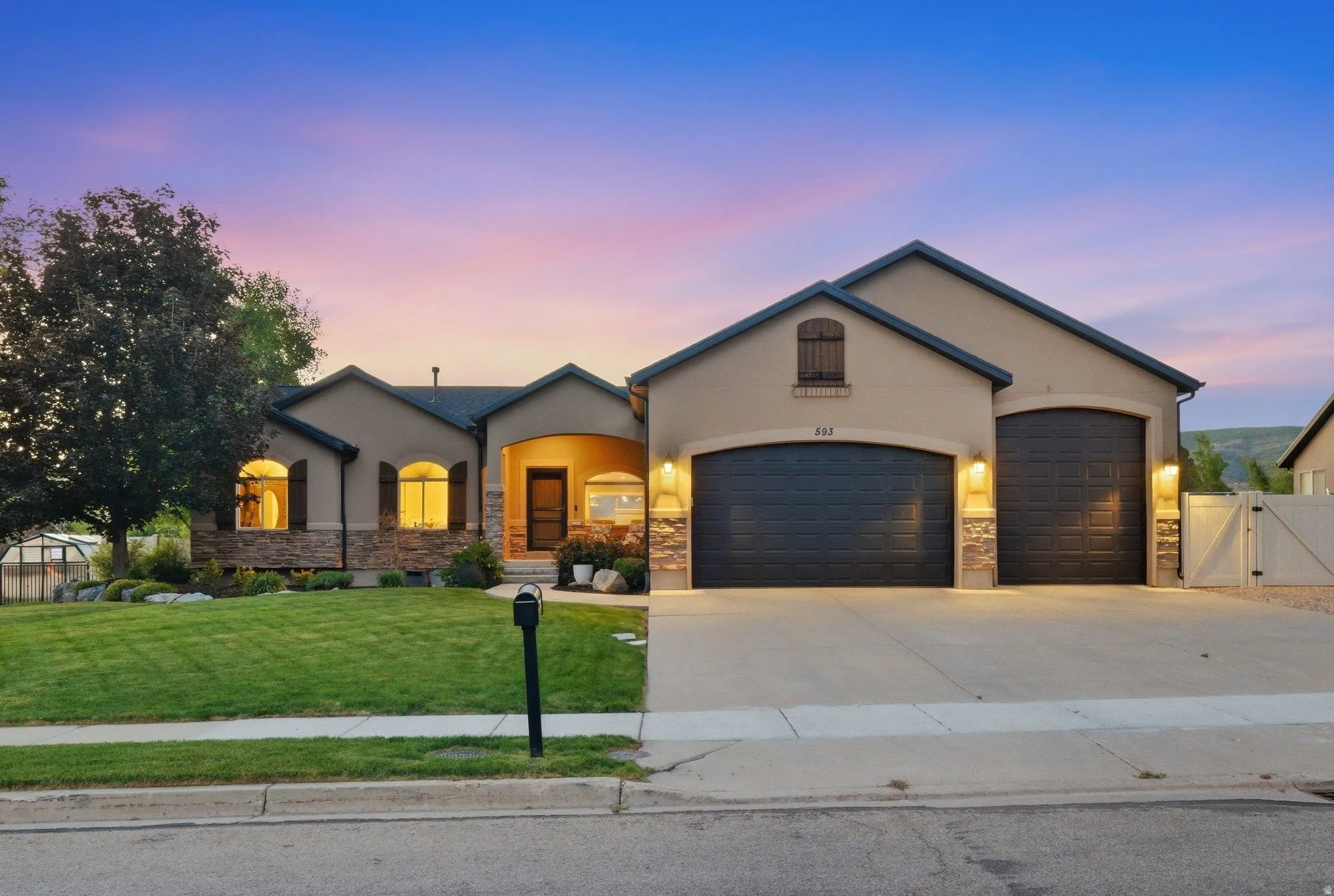 Stucco exterior featuring stone accents, a two-car garage with arched doors, and a covered entryway