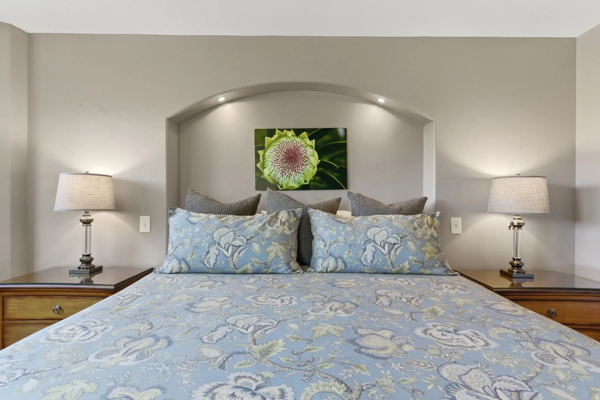 Bedroom featuring a recessed arched niche with integrated lighting, flanked by two built-in nightstands with wood finishes and dark countertops