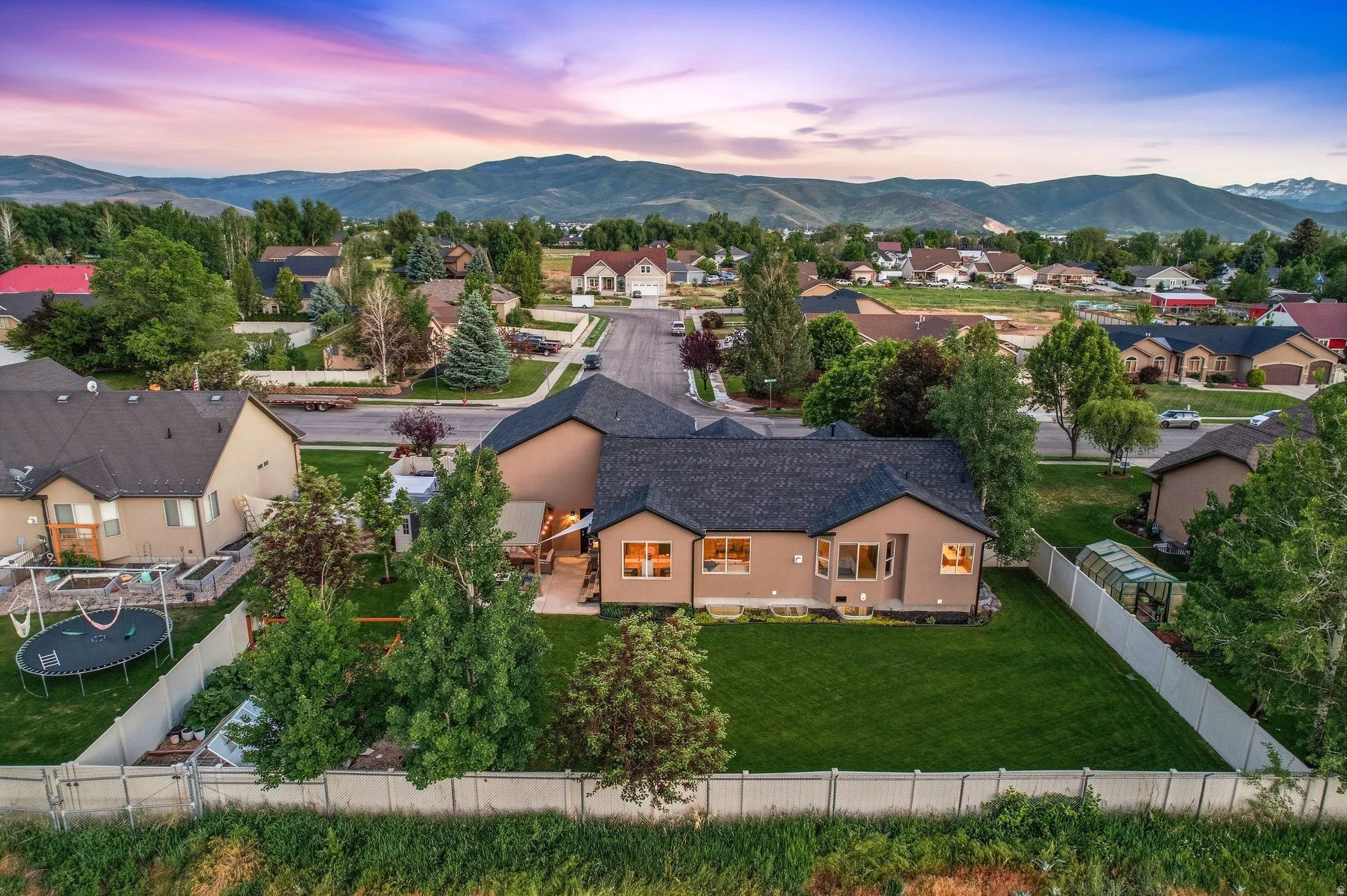 Spacious property featuring a large manicured lawn, a covered patio, and a greenhouse structure