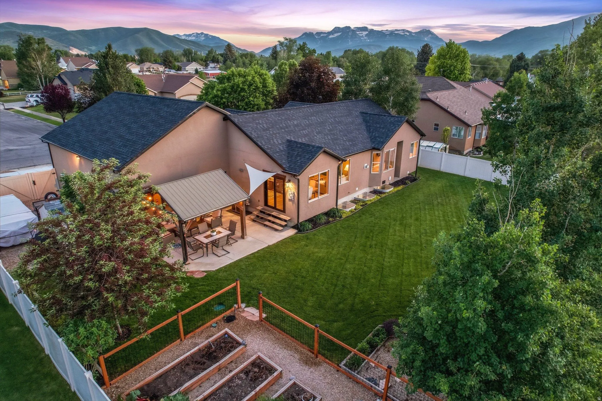 Expansive backyard featuring a large manicured lawn, a covered patio with a metal roof, and a dedicated garden area with raised beds