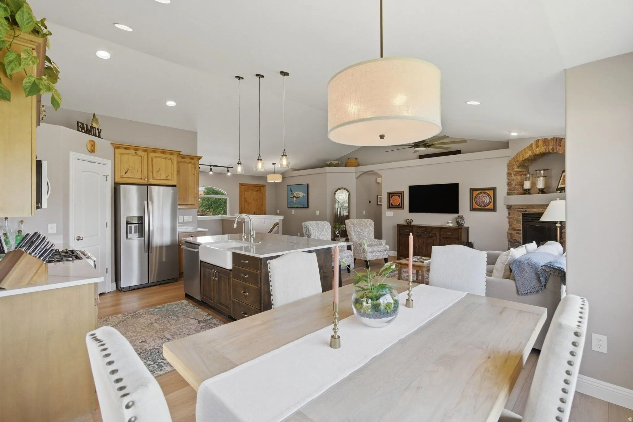 Open-concept living space featuring a kitchen with stainless steel appliances, a center island with a farmhouse sink, and pendant lighting