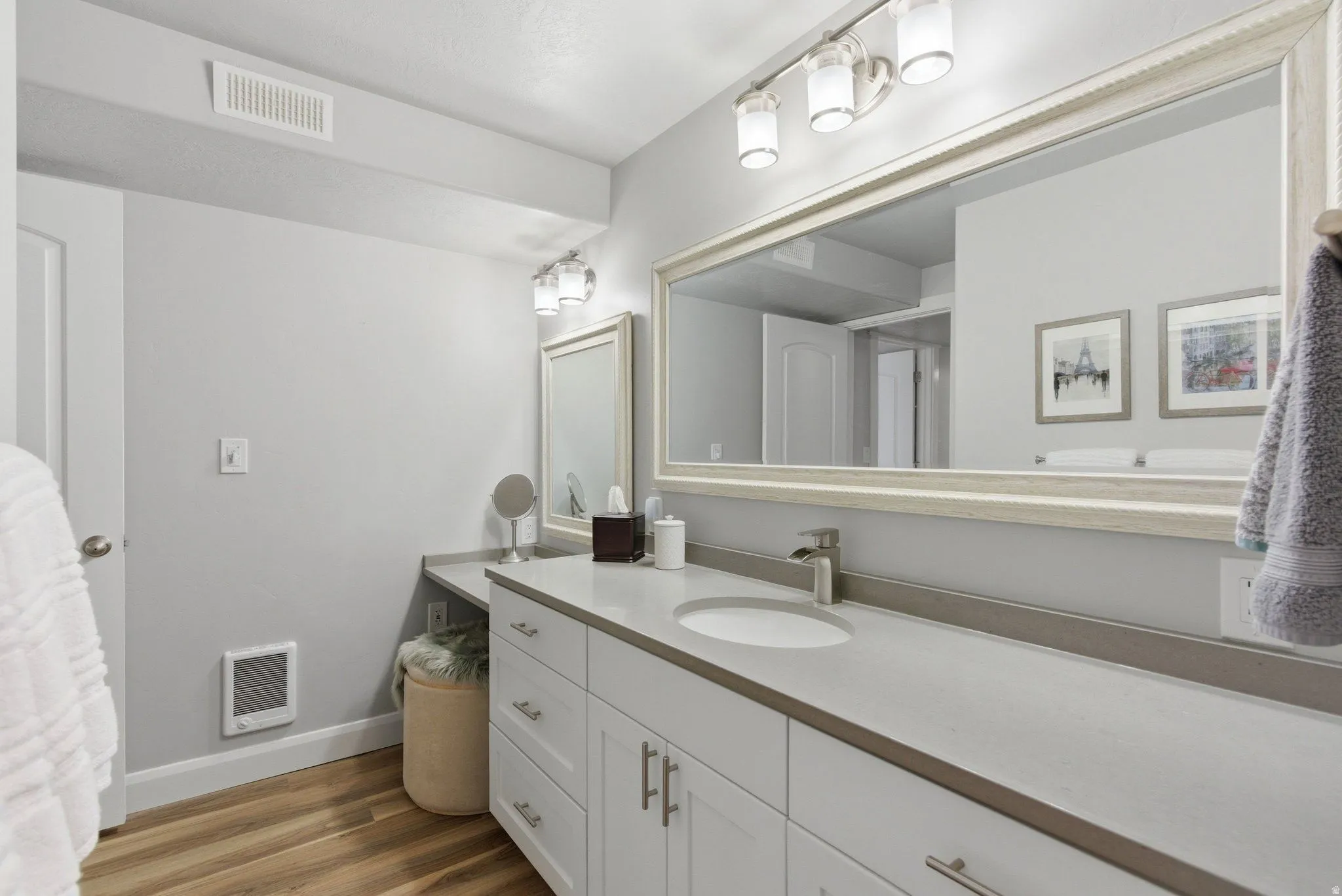 Bathroom featuring an expansive vanity with double sinks, light-toned countertops, and ample storage cabinetry with brushed nickel hardware