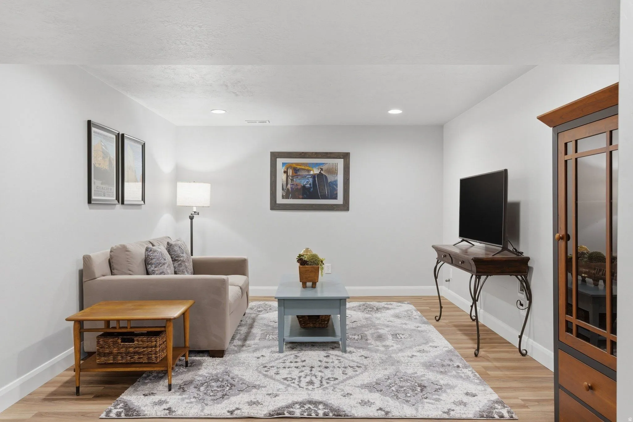Spacious living area featuring light wood-finish flooring, white baseboards, and recessed lighting