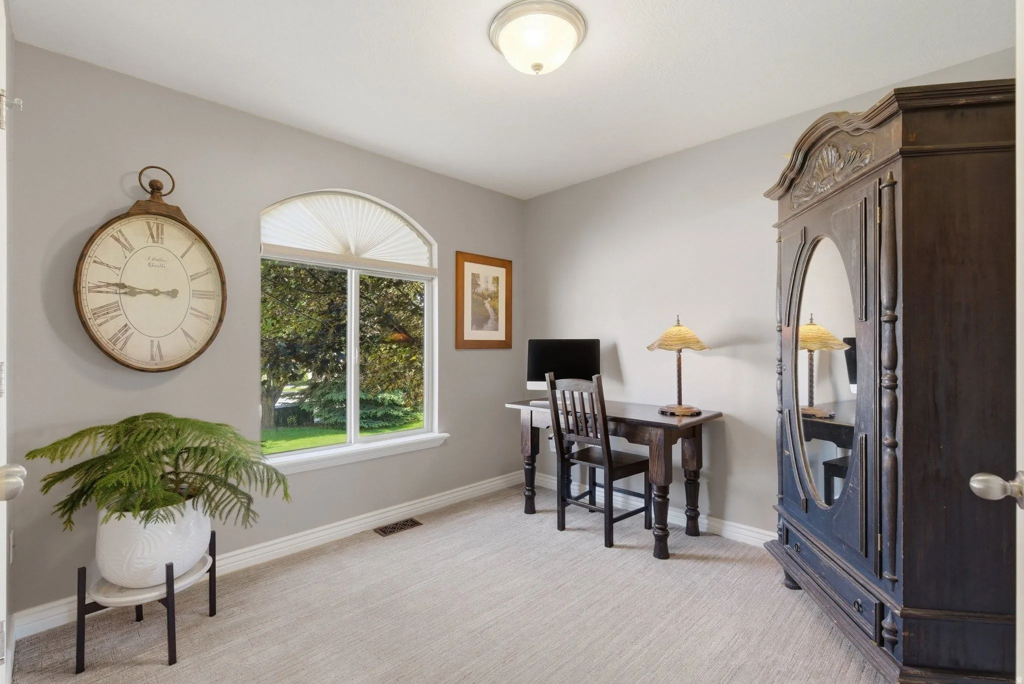 Carpeted room featuring a large arched window with exterior tree views, light gray wall paint, and white baseboards
