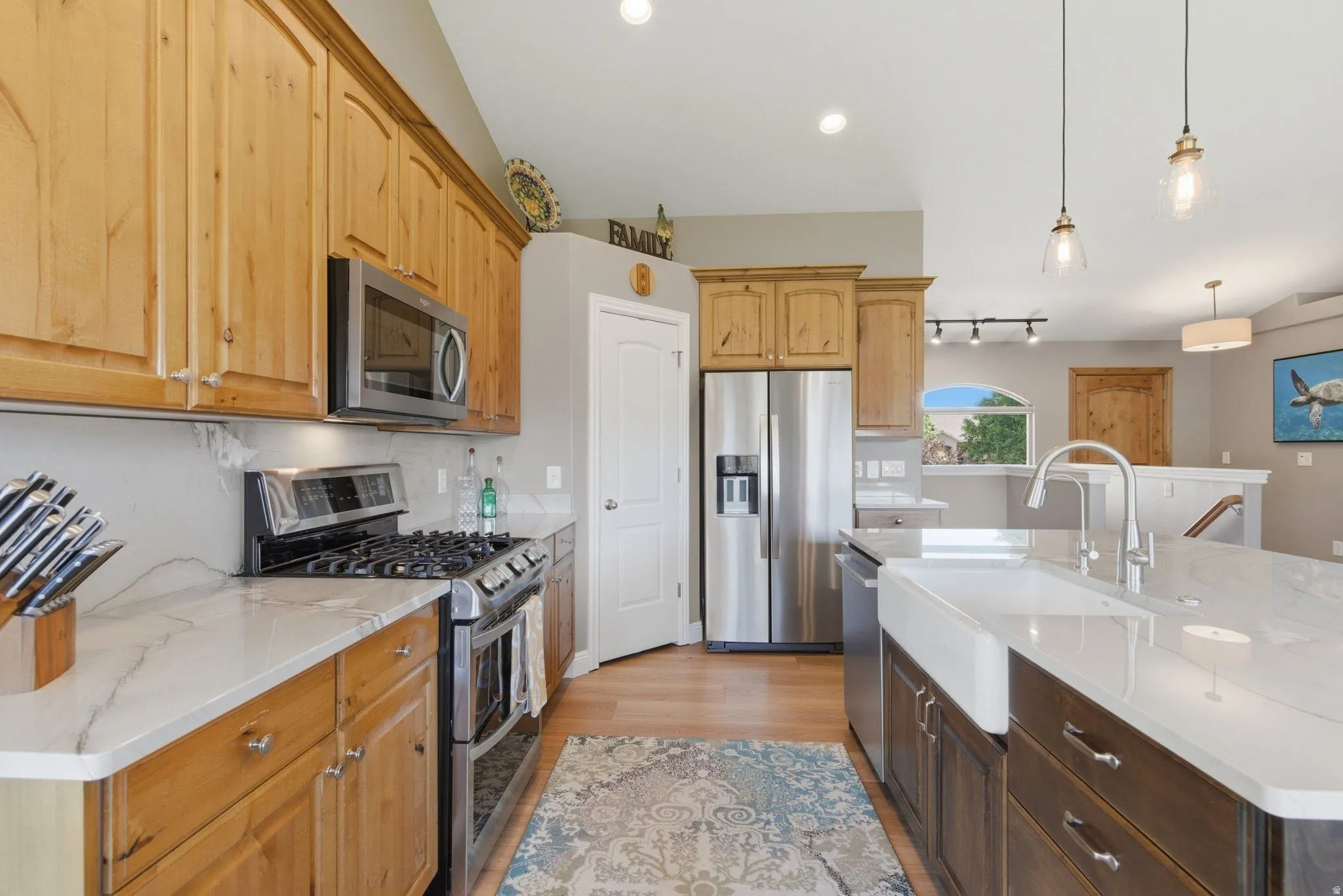 Kitchen featuring light wood cabinetry, stainless steel appliances, a gas range with an oven, and white countertops