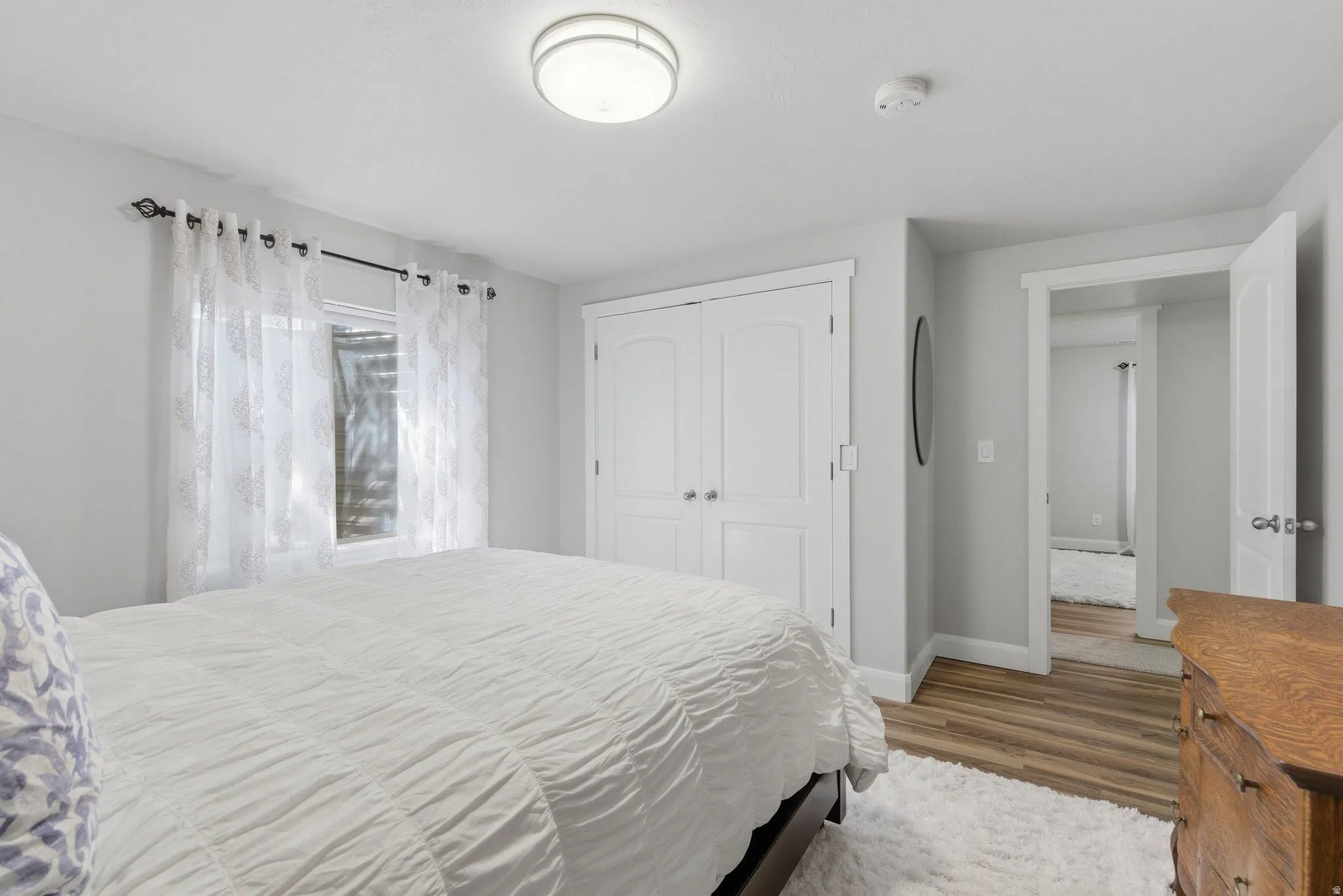 Bedroom featuring wood-finish flooring, light grey walls, white trim, and a window with white blinds