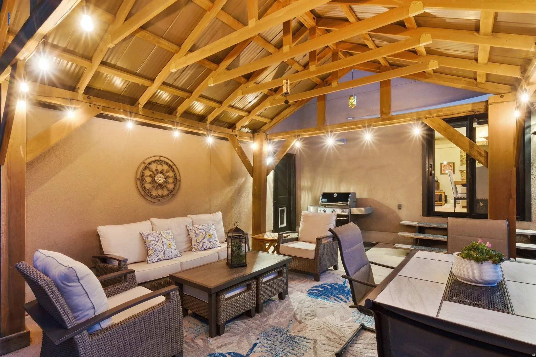 Covered patio featuring an exposed wood beam ceiling, corrugated metal roofing, and string lighting