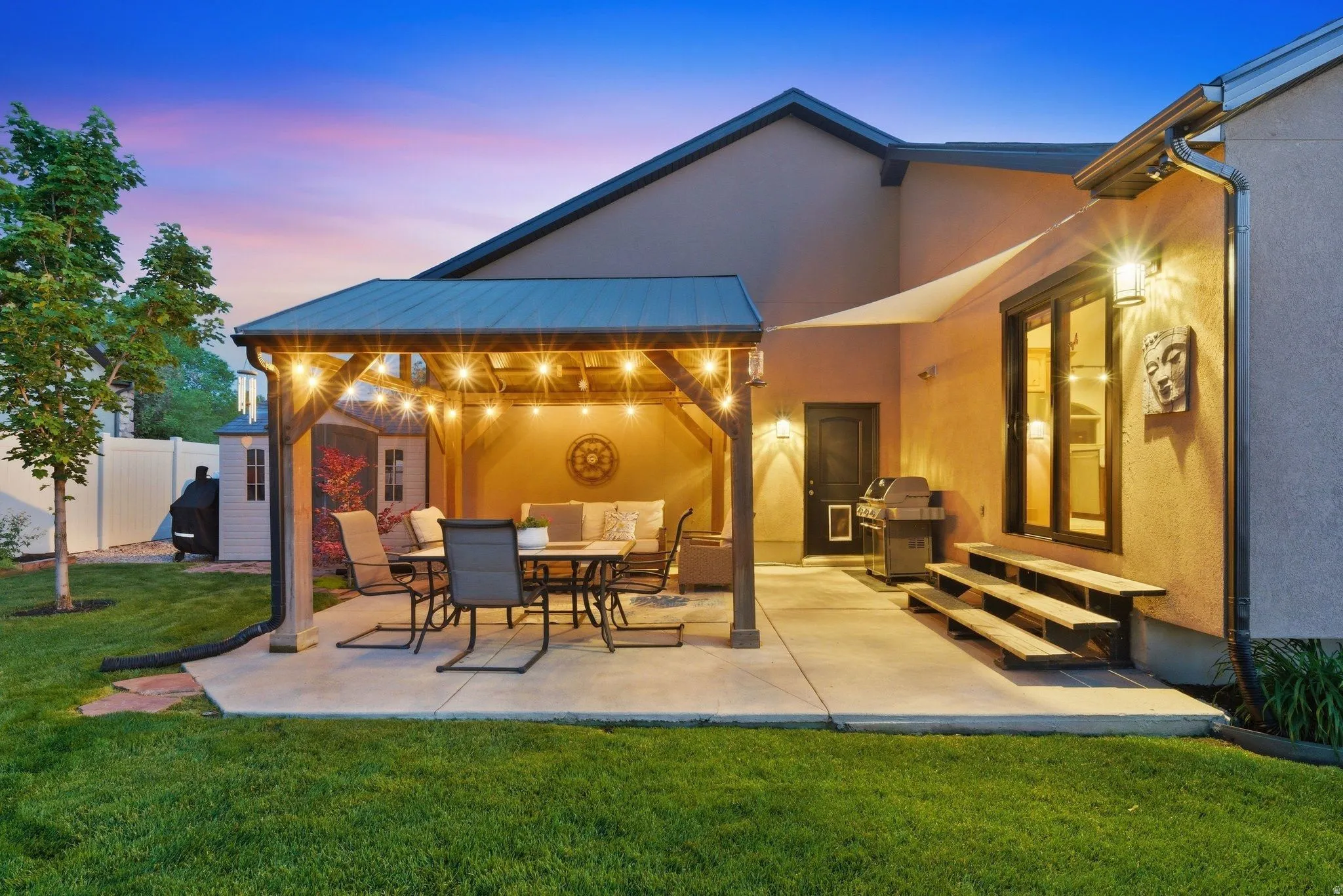 Expansive concrete patio featuring a covered pergola with string lighting, a shade sail, and direct exterior access