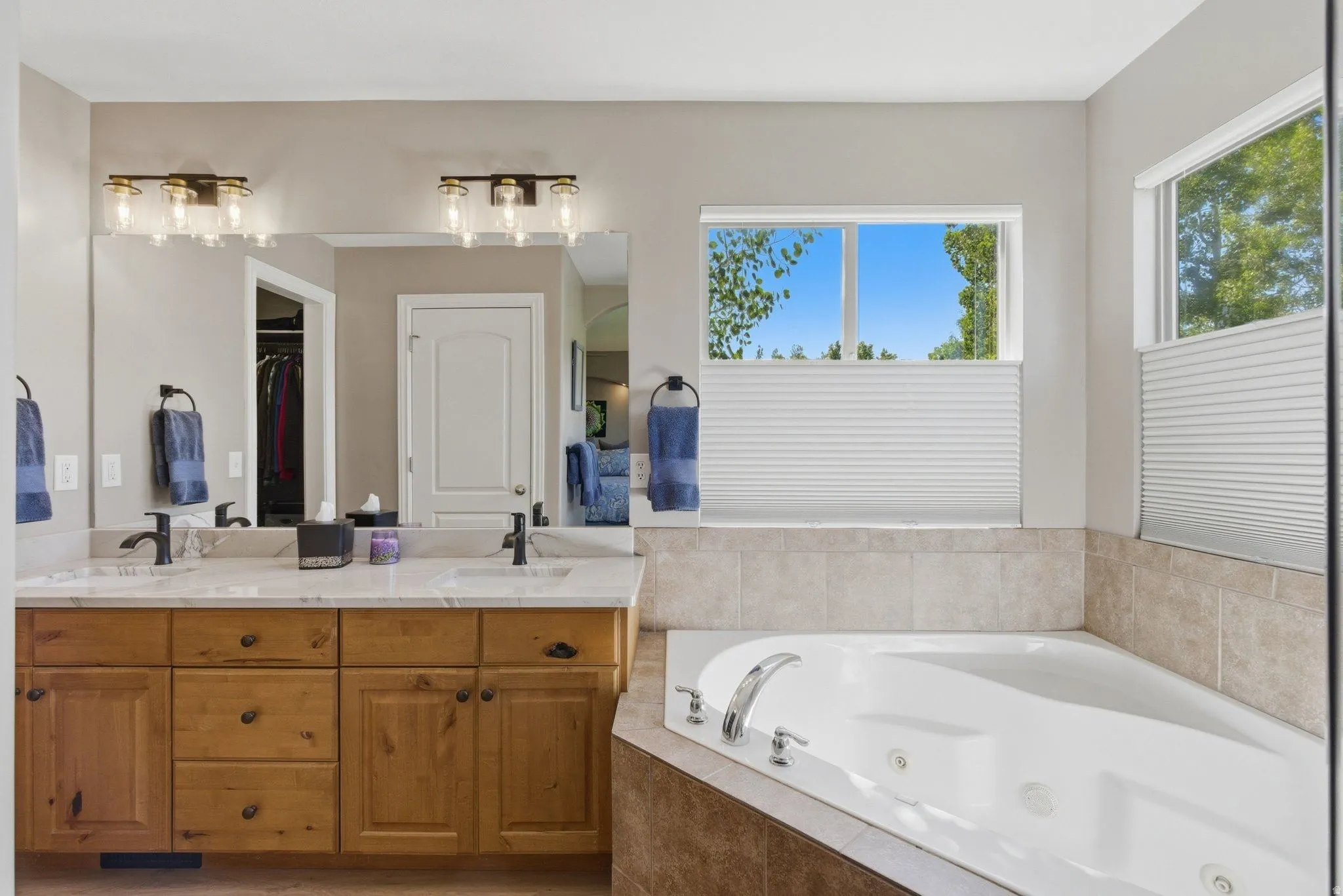 Spacious bathroom featuring a dual vanity with light-toned wood cabinetry and a light-toned countertop