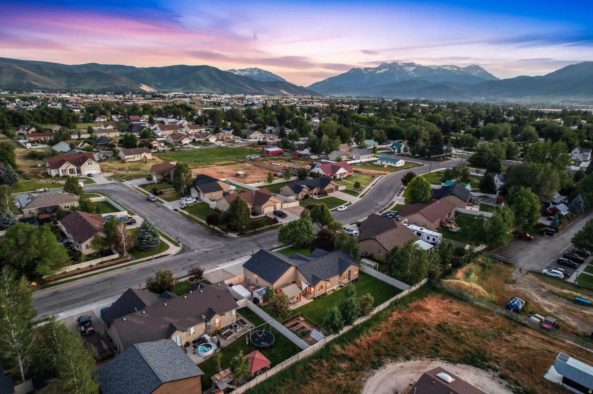 Residential neighborhood featuring mature trees, paved streets, and a mountainous backdrop