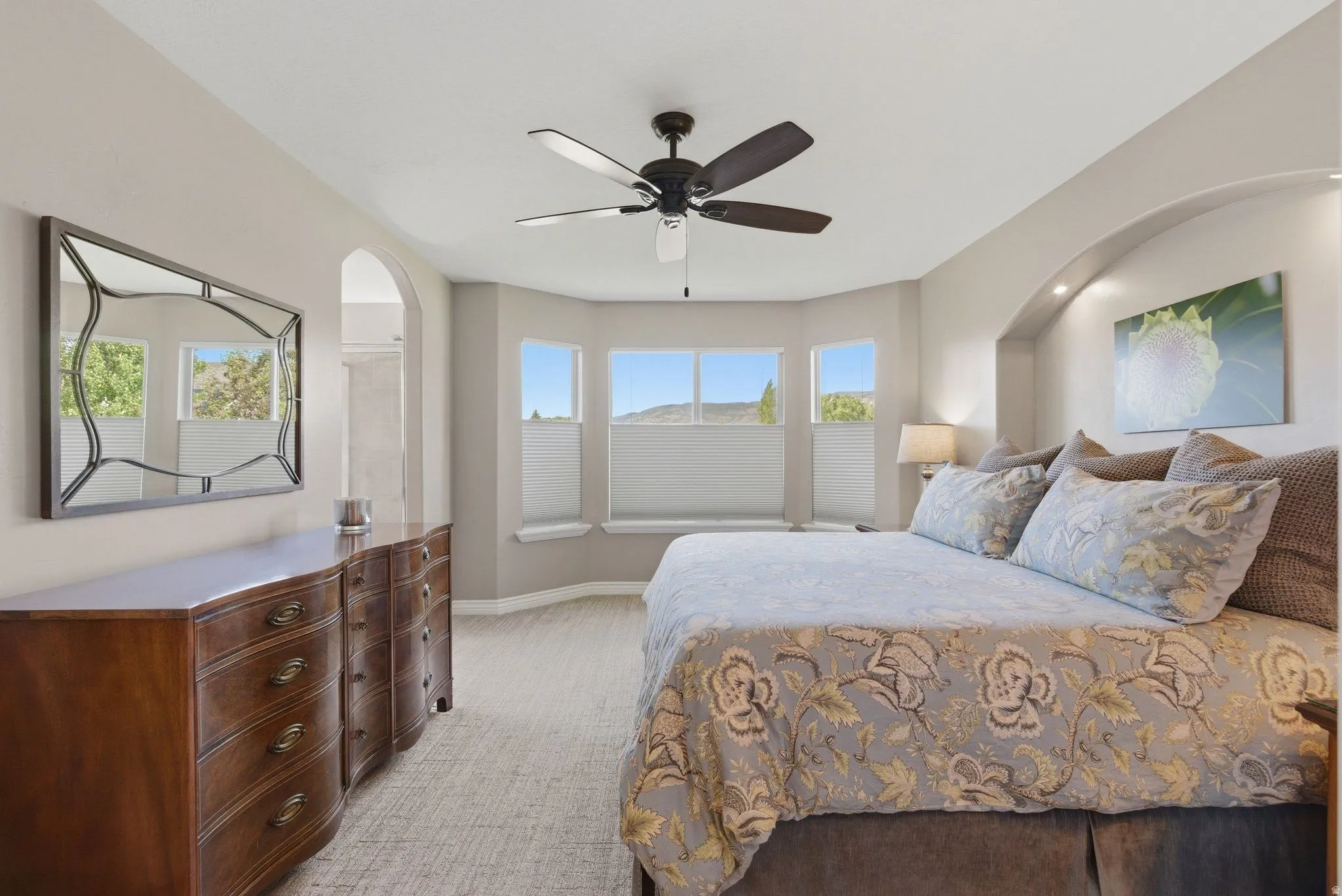 Spacious room featuring a tray ceiling with a ceiling fan, a bay window with a built-in bench, and arched architectural details