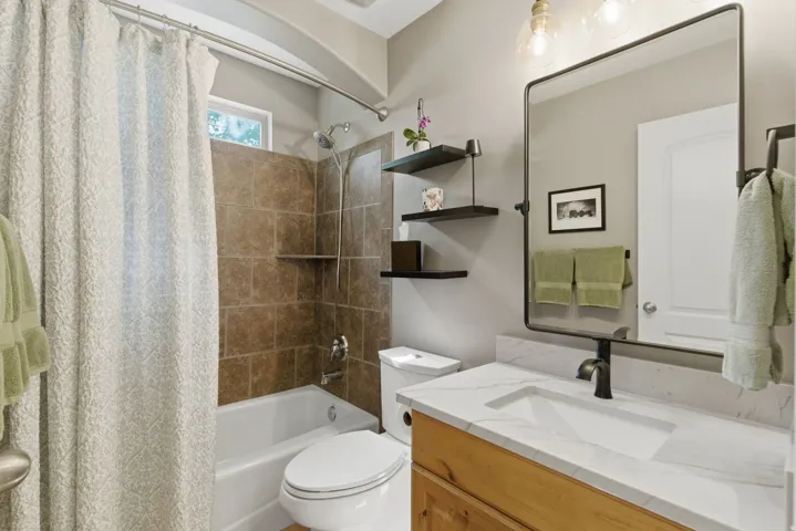 Bathroom featuring a tub/shower combination with brown subway tile surround, a built-in shower shelf, and a window