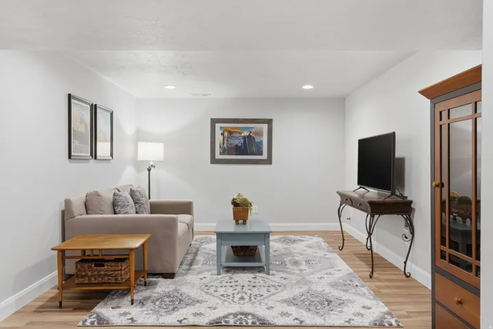 Spacious living area featuring light wood-finish flooring, white baseboards, and recessed lighting