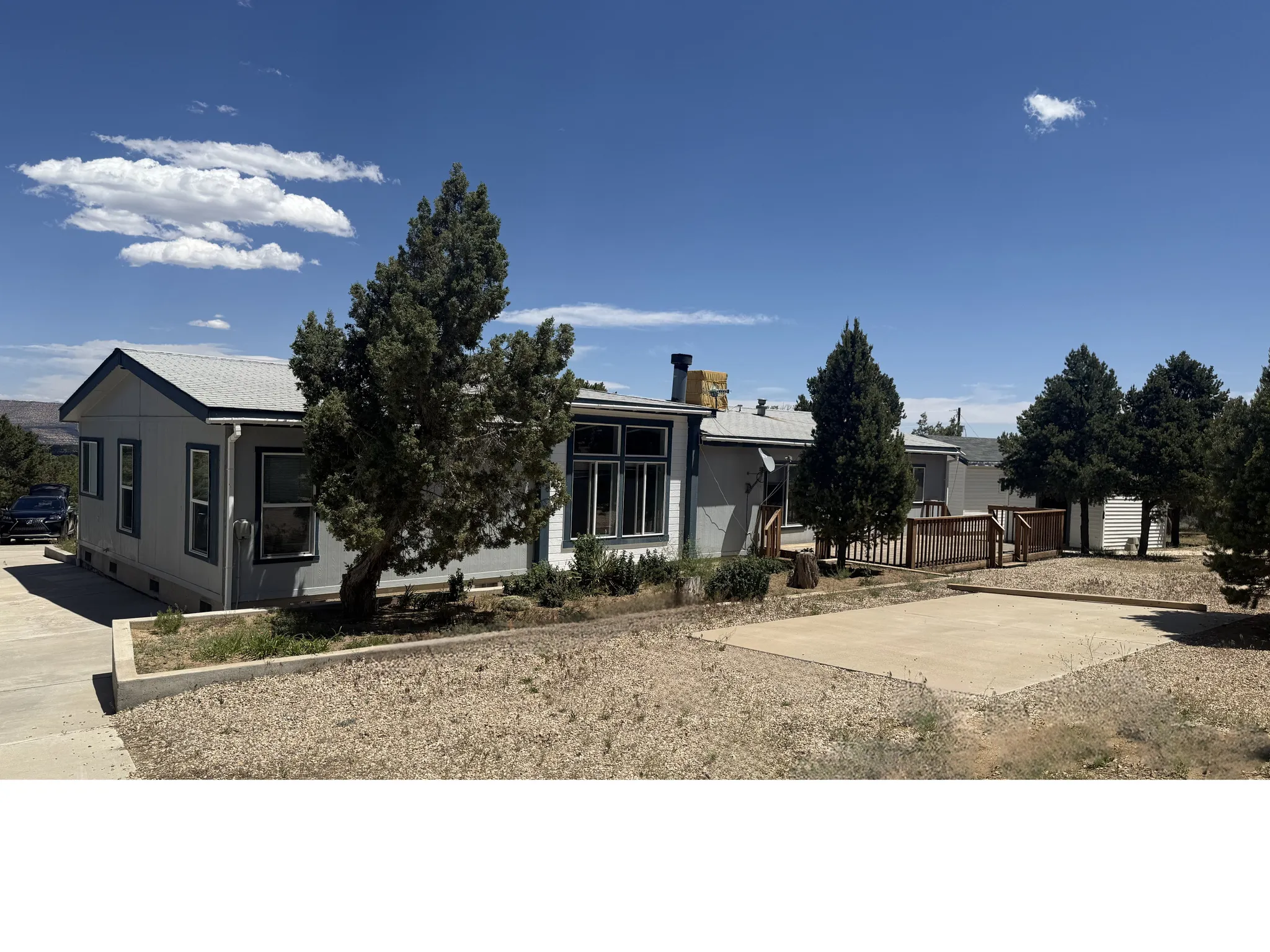 Exterior featuring light gray siding with dark trim, multiple windows, and a paved driveway
