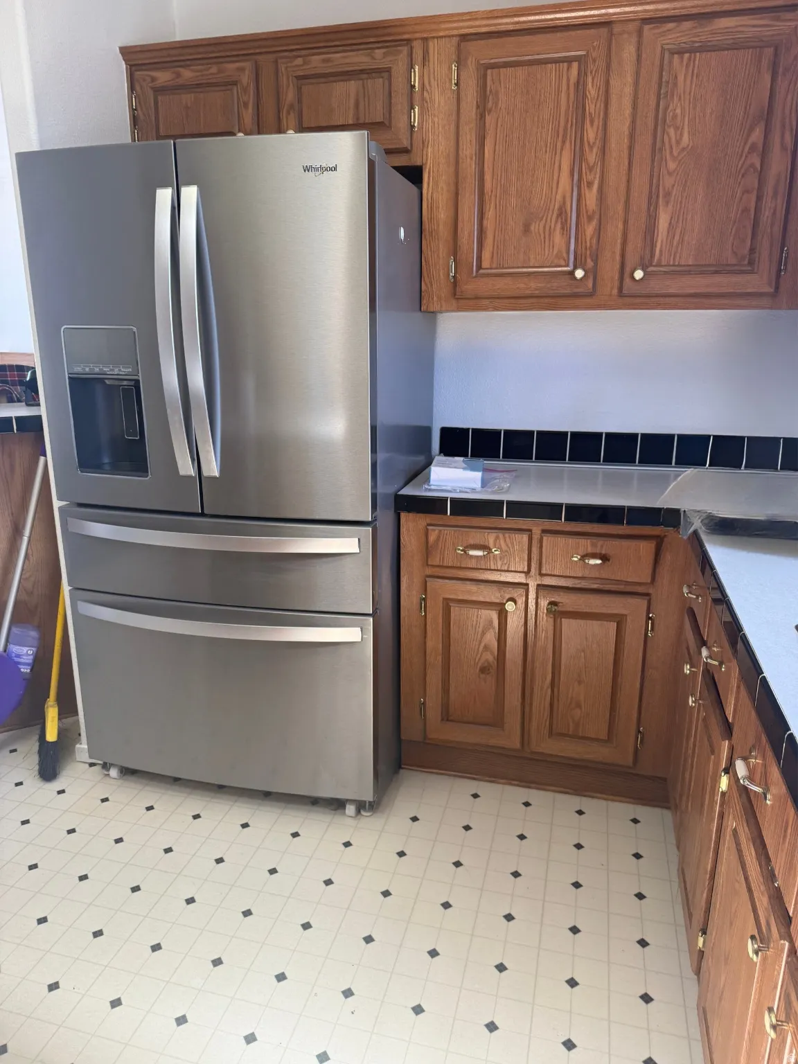 Kitchen featuring wood cabinetry, solid surface countertops, and patterned vinyl flooring