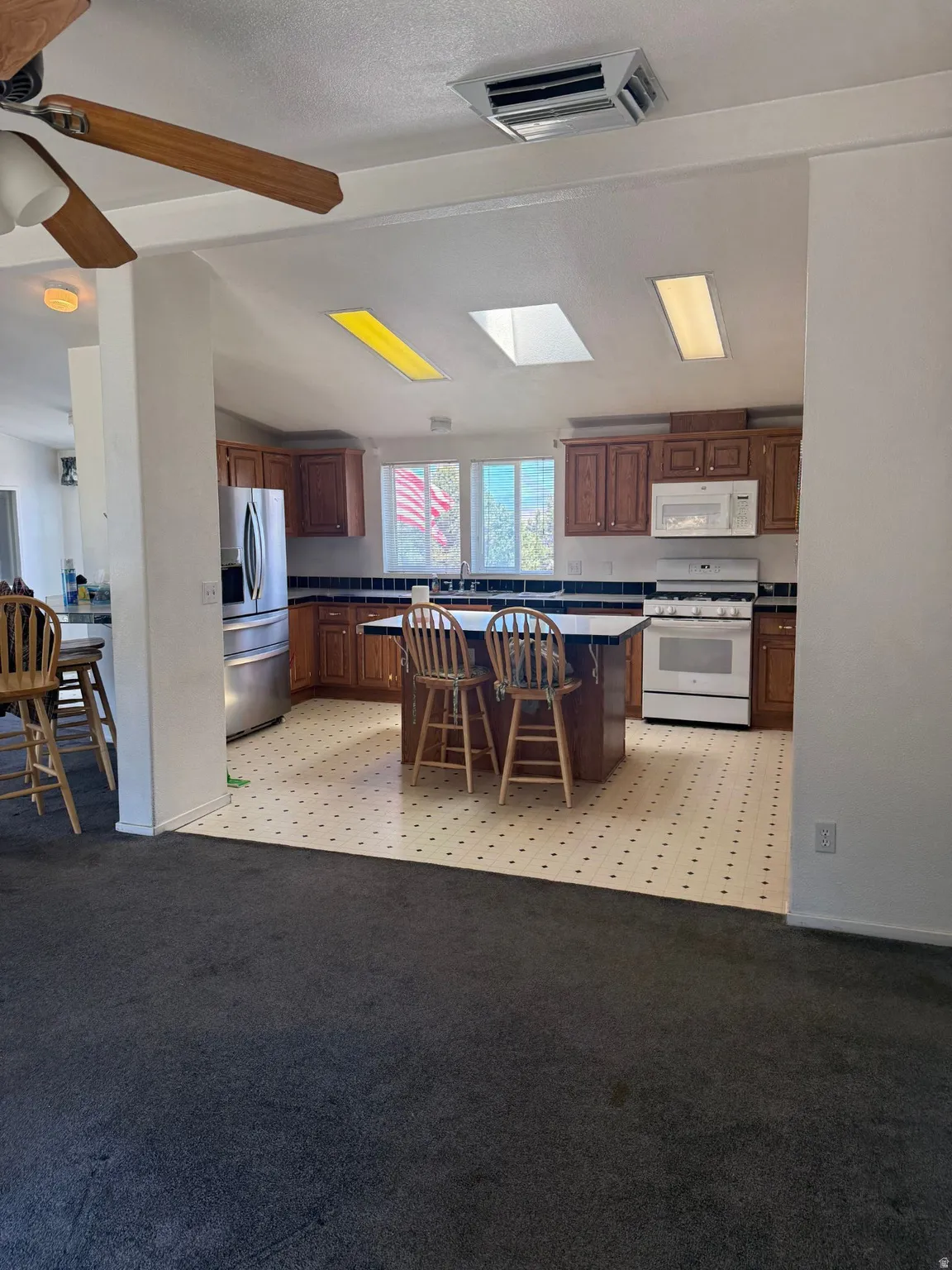 Kitchen featuring wood cabinetry, stainless steel refrigerator, and white range with matching microwave