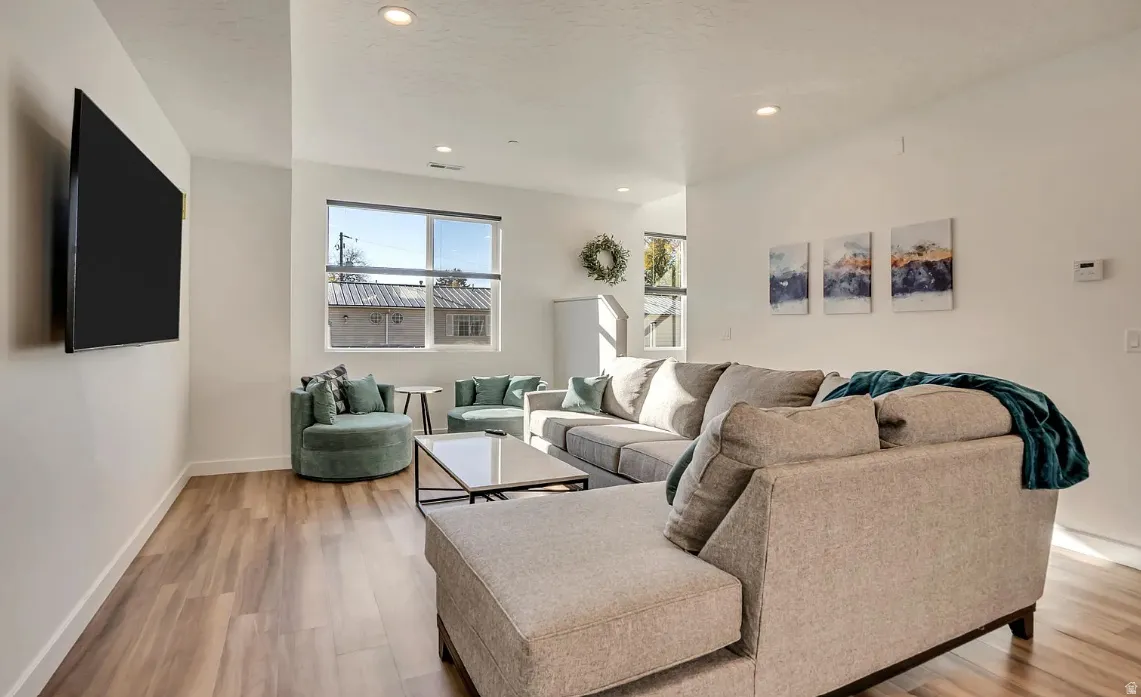 Living area featuring wood-finish flooring, recessed lighting, and a large window