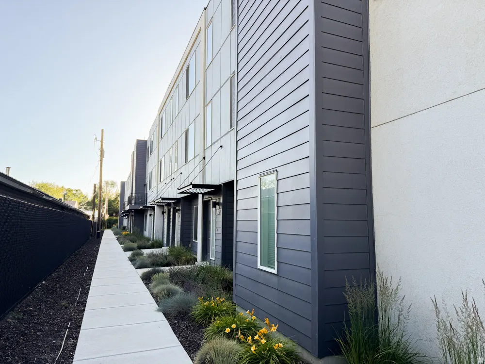 Modern multi-story building featuring dark gray horizontal siding and white stucco accents