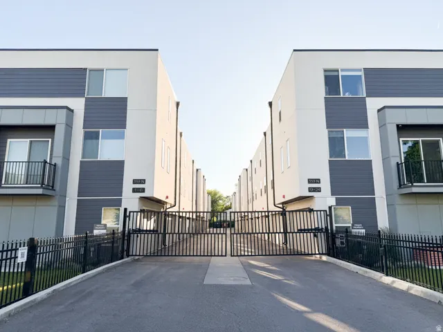 Modern building exterior featuring a neutral color palette with dark gray siding accents and white stucco