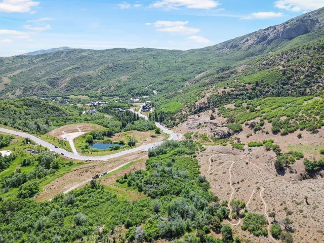 Expansive mountain landscape featuring varied topography, a serene pond, and paved roadways