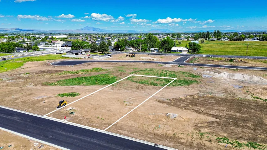 Cleared lot with established road frontage, infrastructure, and distant mountain backdrop