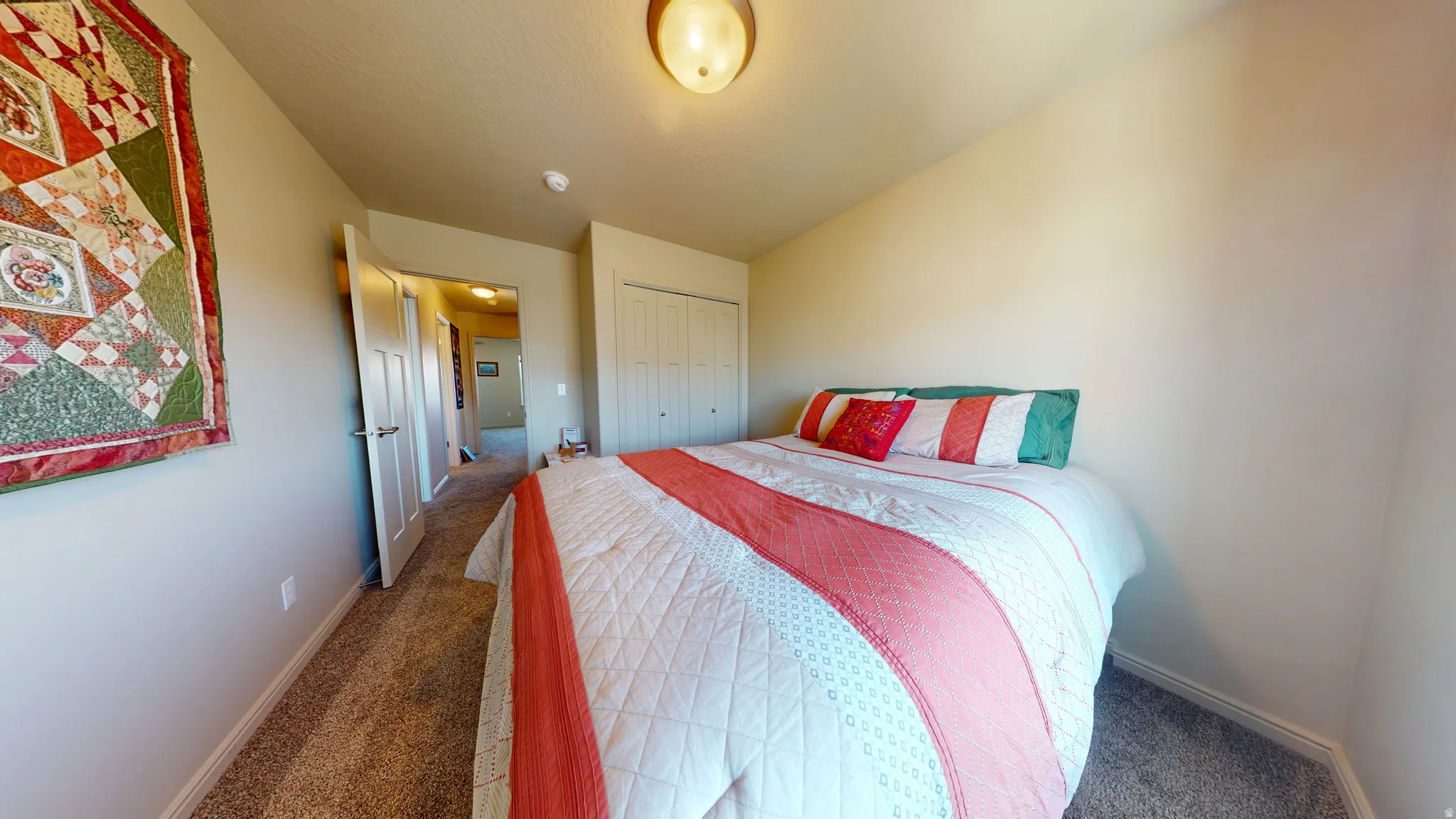 Carpeted room featuring a ceiling-mounted light fixture, white trim, and a bi-fold closet door