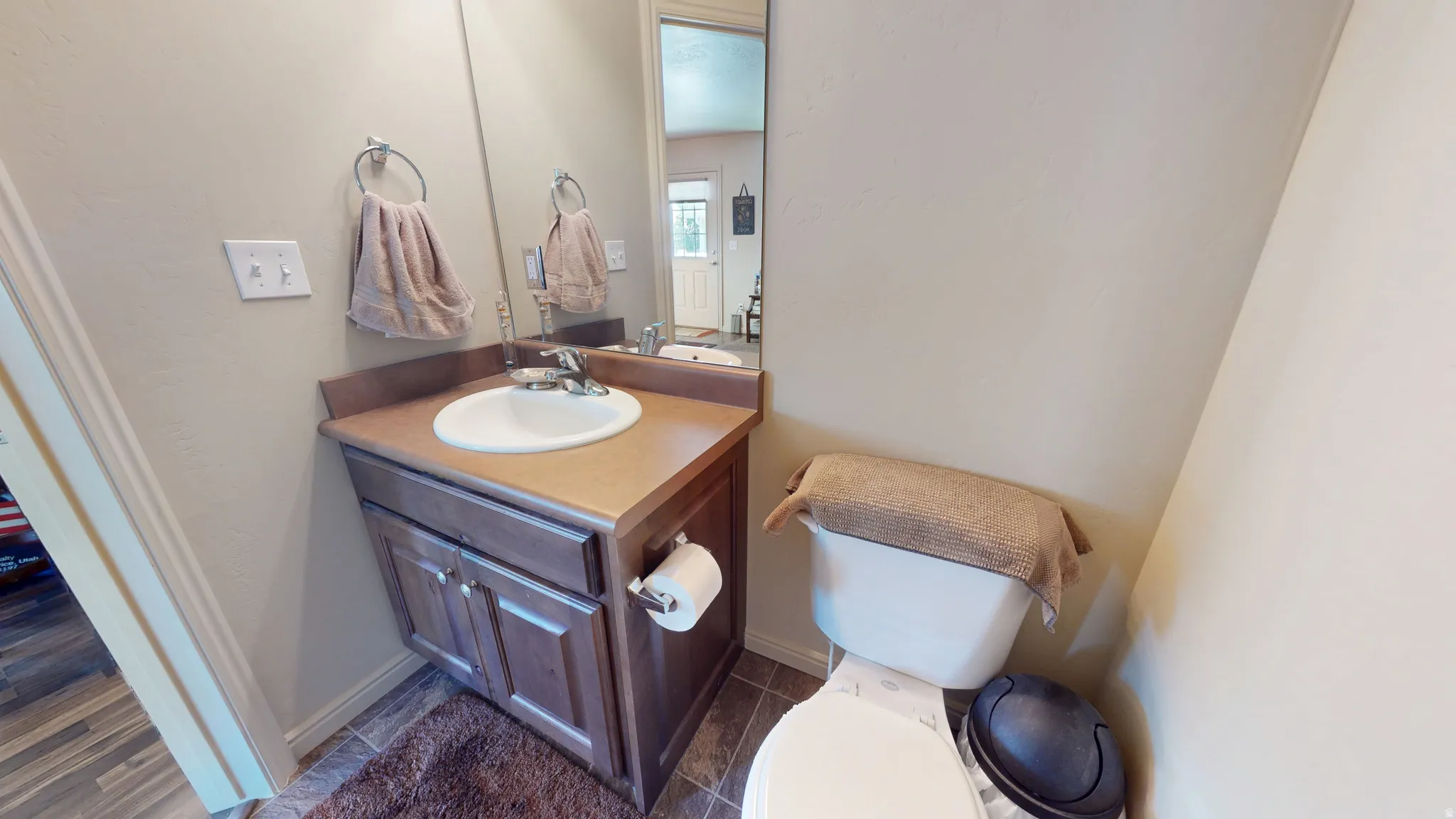 Bathroom featuring a wood-finish vanity with an integrated sink and laminate countertop