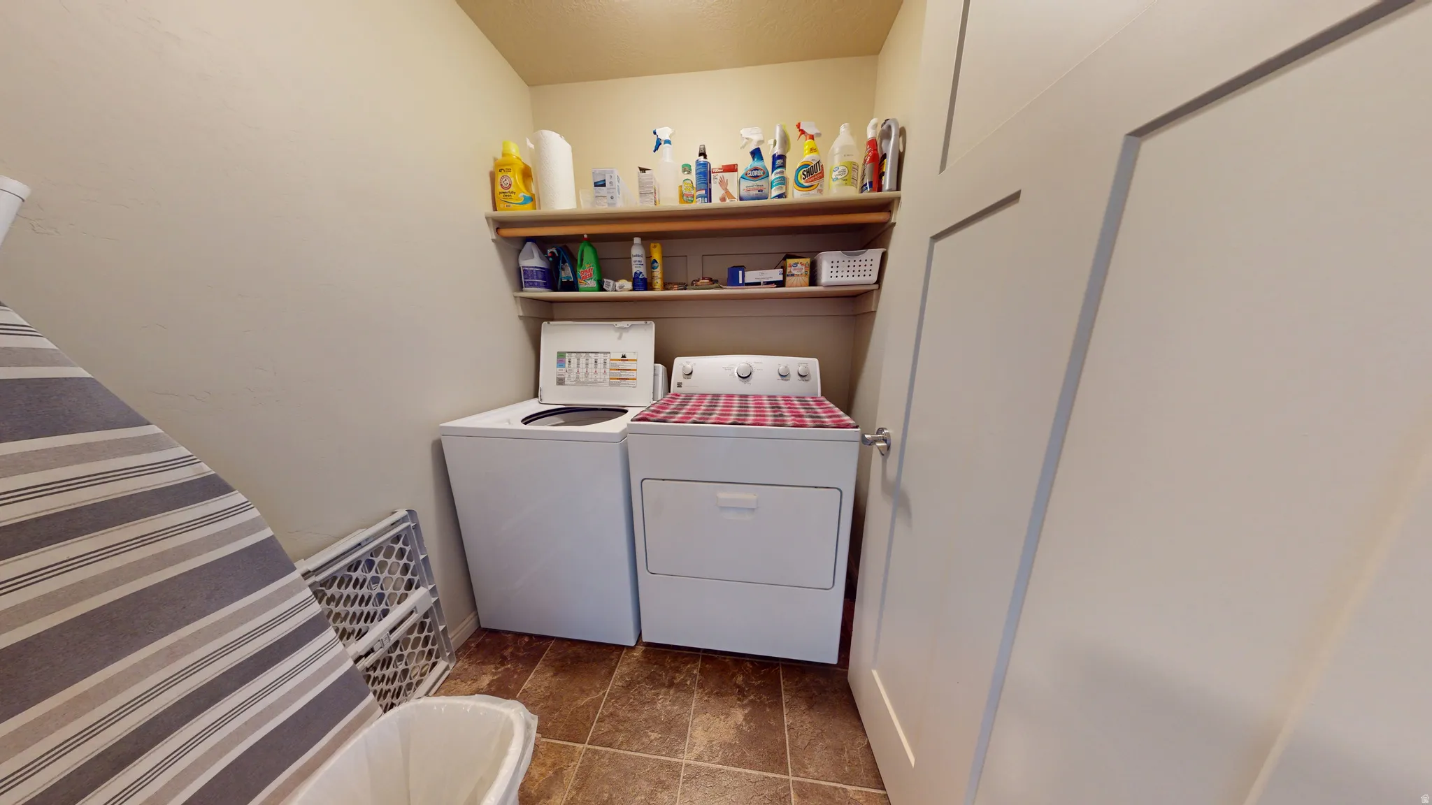 Dedicated laundry area featuring a top-load washing machine, front-load dryer, and built-in shelving