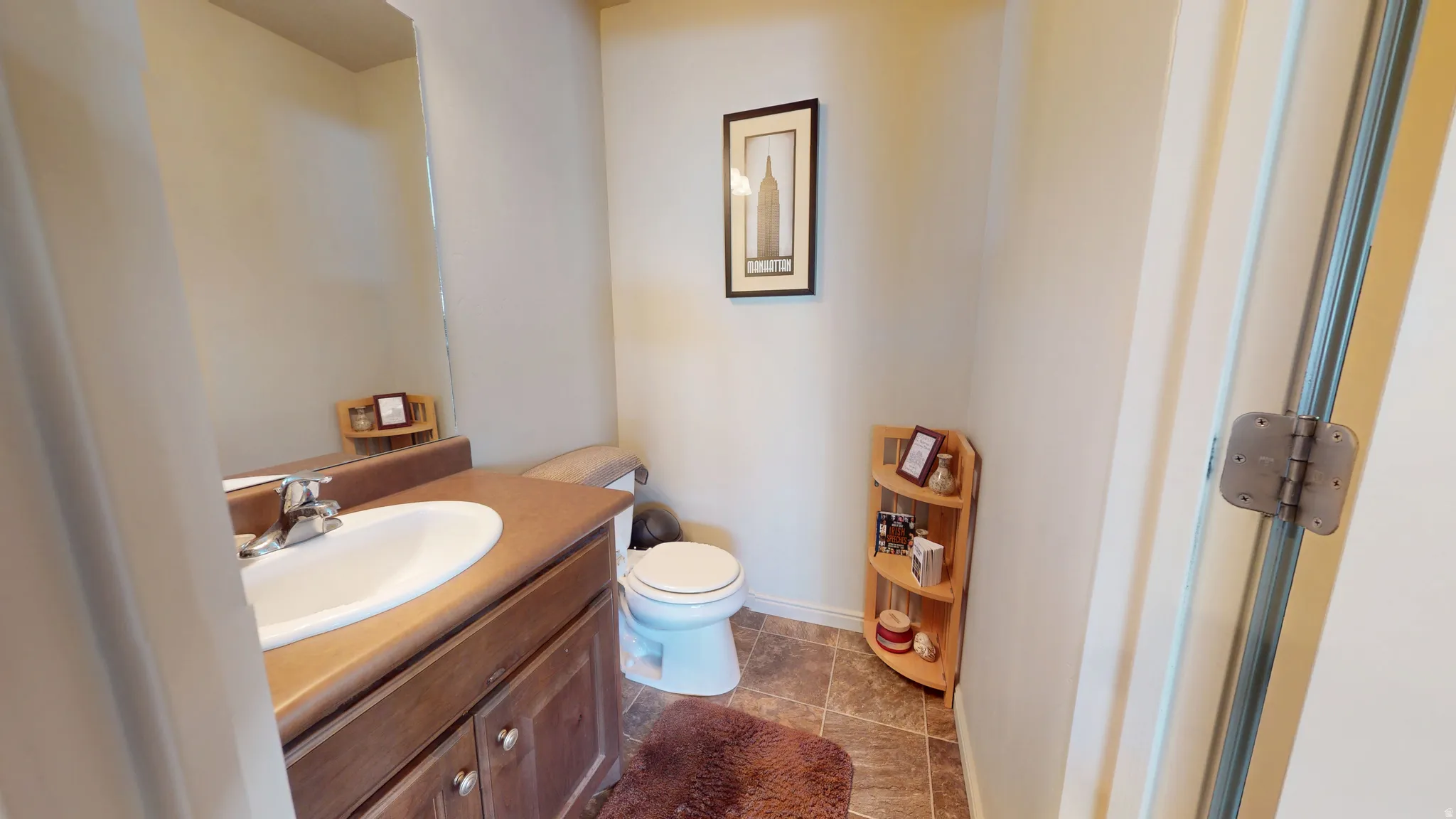 Bathroom featuring a wood-finish vanity with a single basin sink and chrome faucet