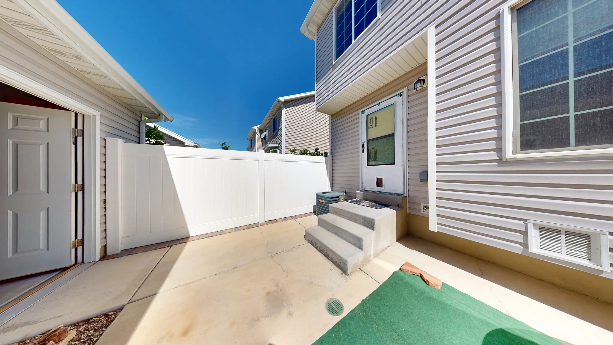 Rear exterior featuring light-colored siding, concrete patio, and a white privacy fence