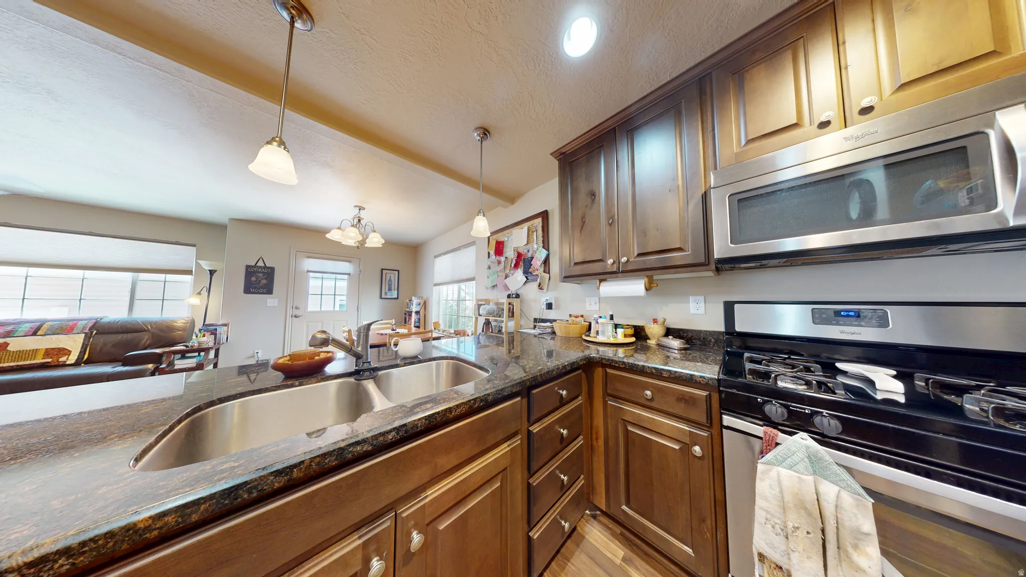 Kitchen featuring dark wood cabinetry, a double basin stainless steel sink, and dark granite countertops