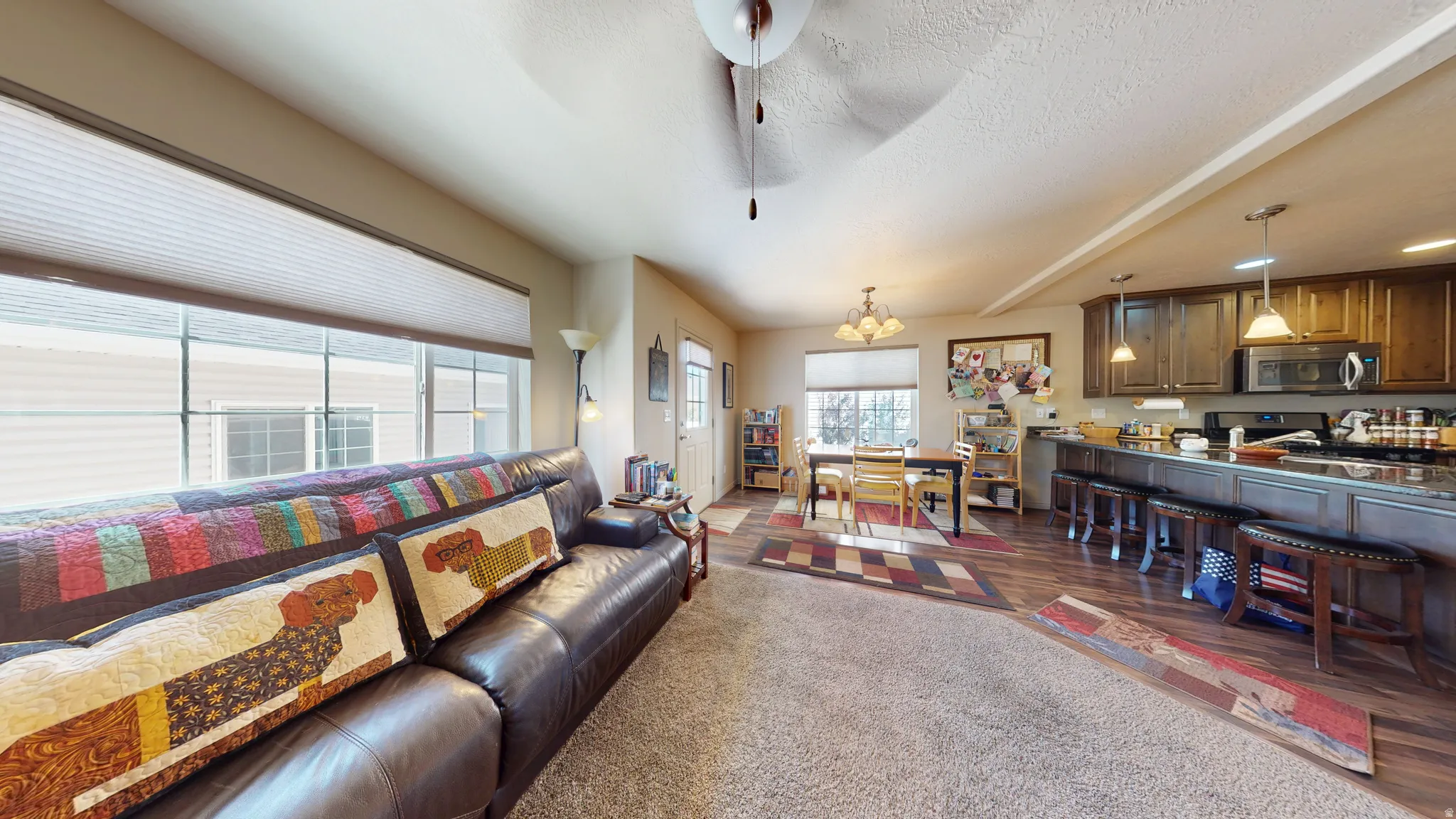 Open concept living area featuring a kitchen with dark cabinetry, stainless steel appliances, and a breakfast bar
