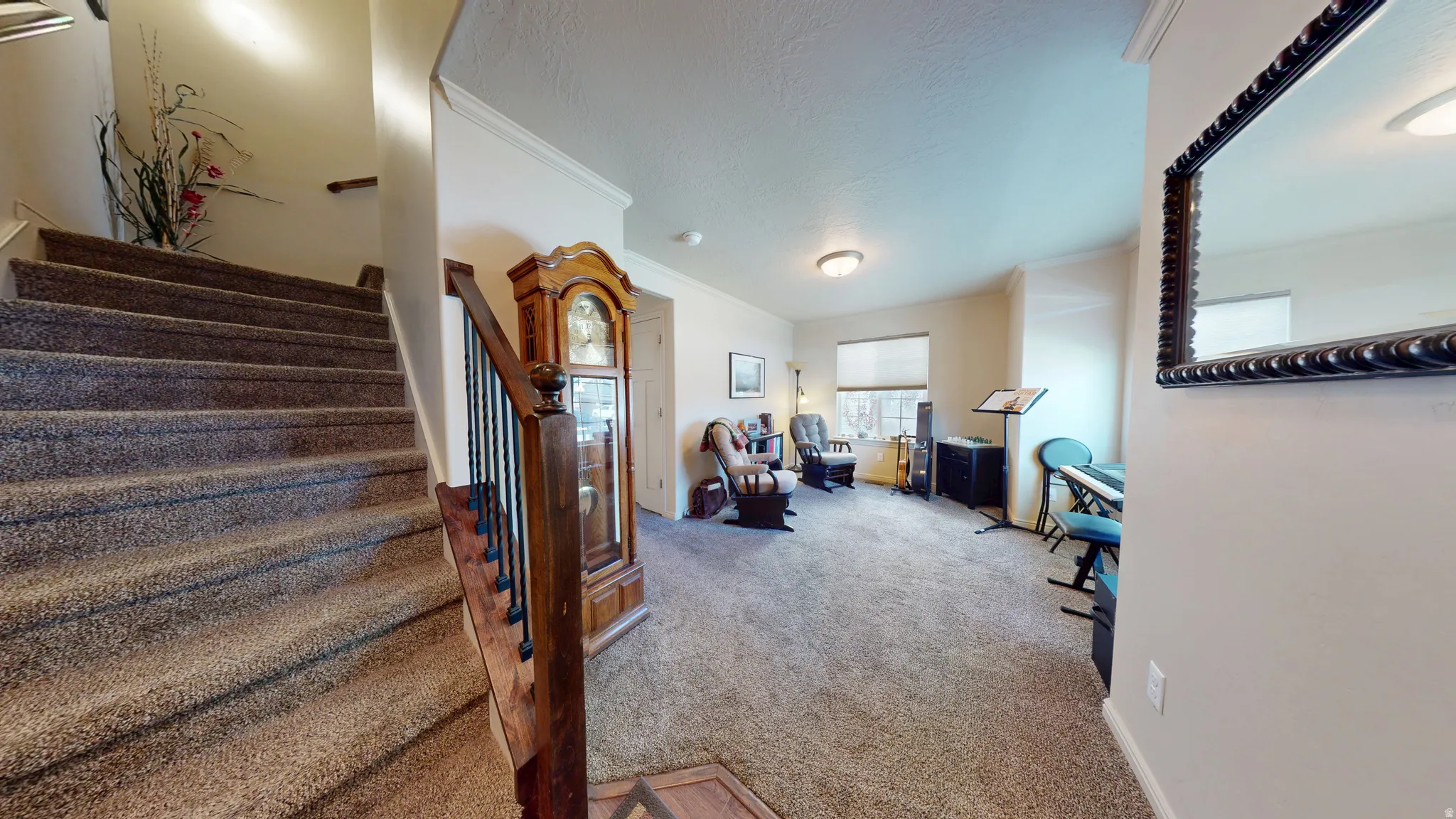 Carpeted staircase with wood handrail and wrought iron balusters
