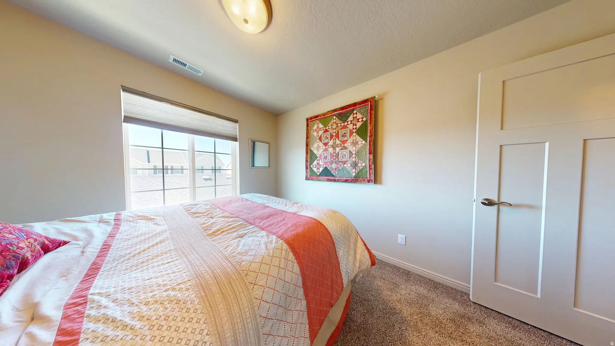Spacious room featuring a large window, neutral wall paint, textured carpeting, and a contemporary two-panel interior door